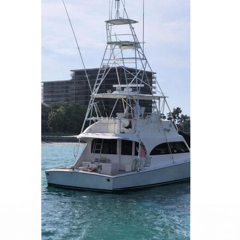 1999 Post 50 yacht with tall tower, docked near modern buildings and palm trees.