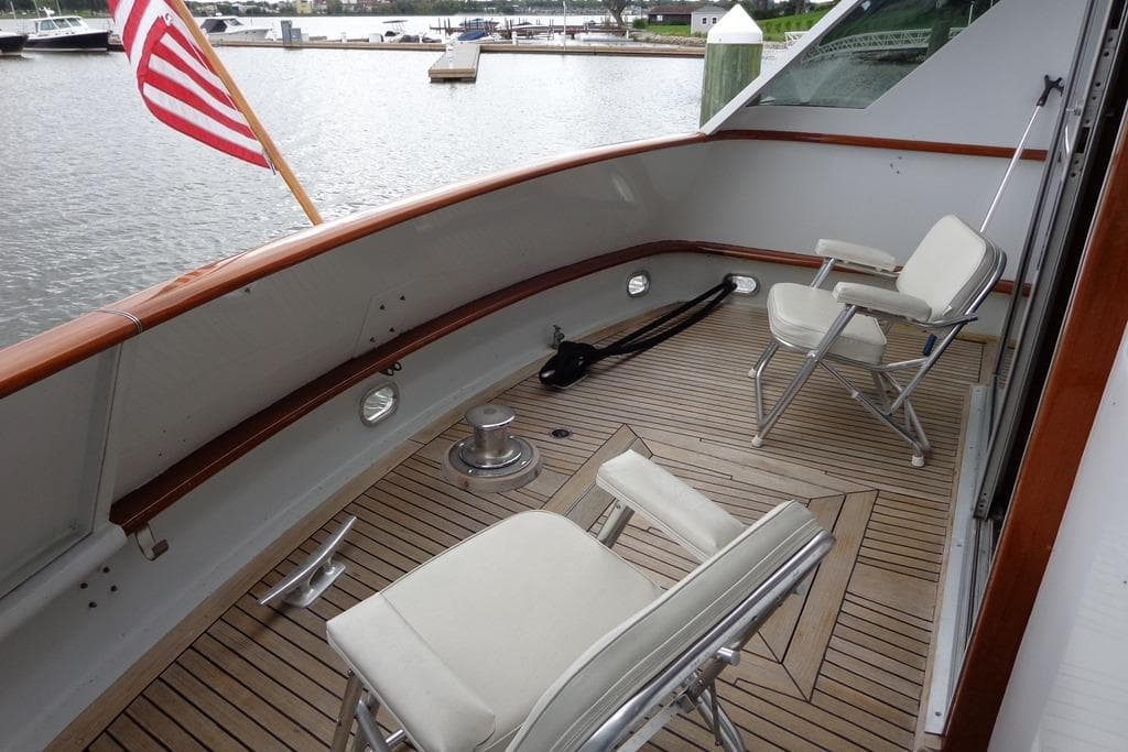 1988 Burger 80 Motor Yacht deck with chairs and American flag, docked by the water.
