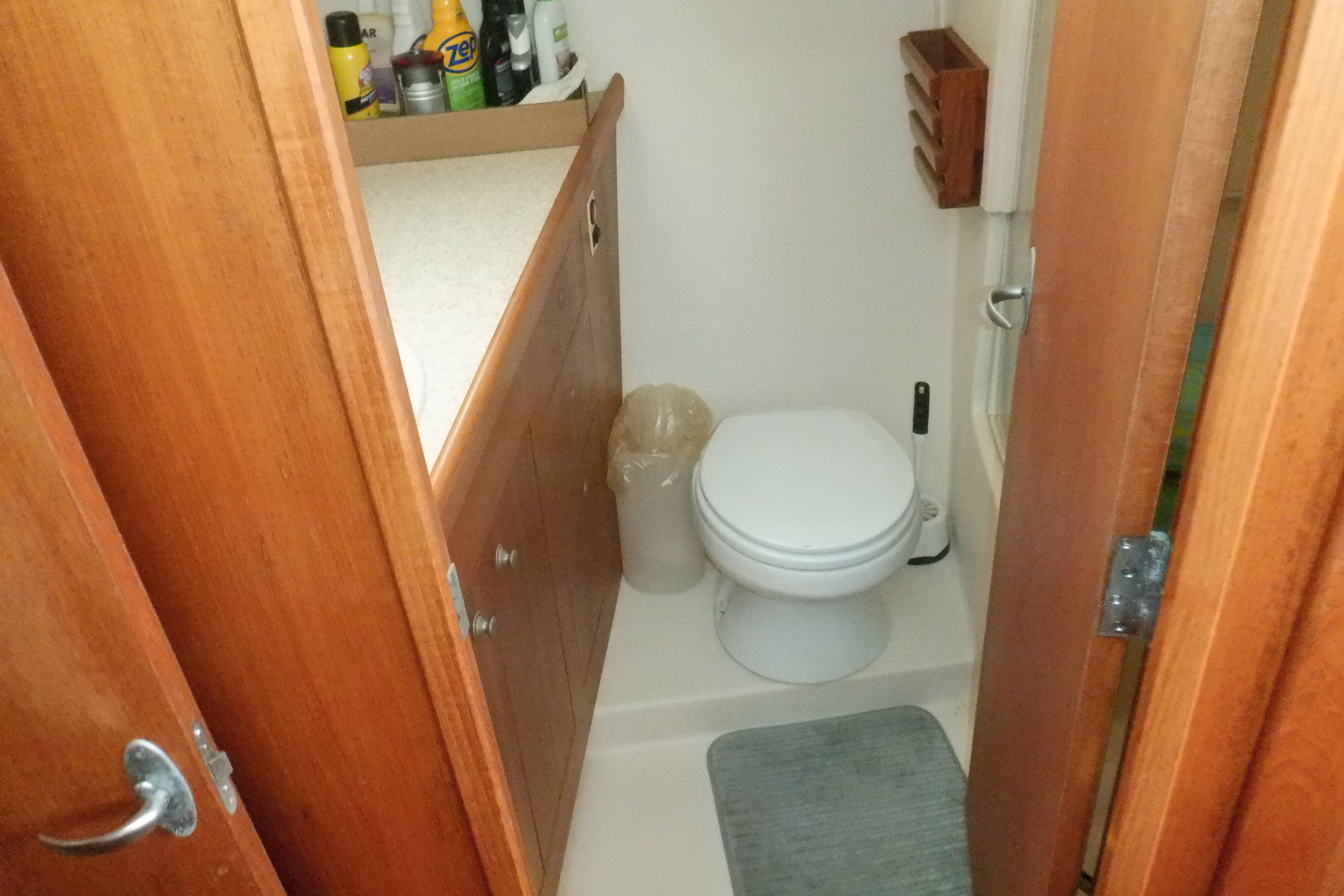 Bathroom interior of 2002 Mainship 430 Trawler with wooden cabinetry and toilet.