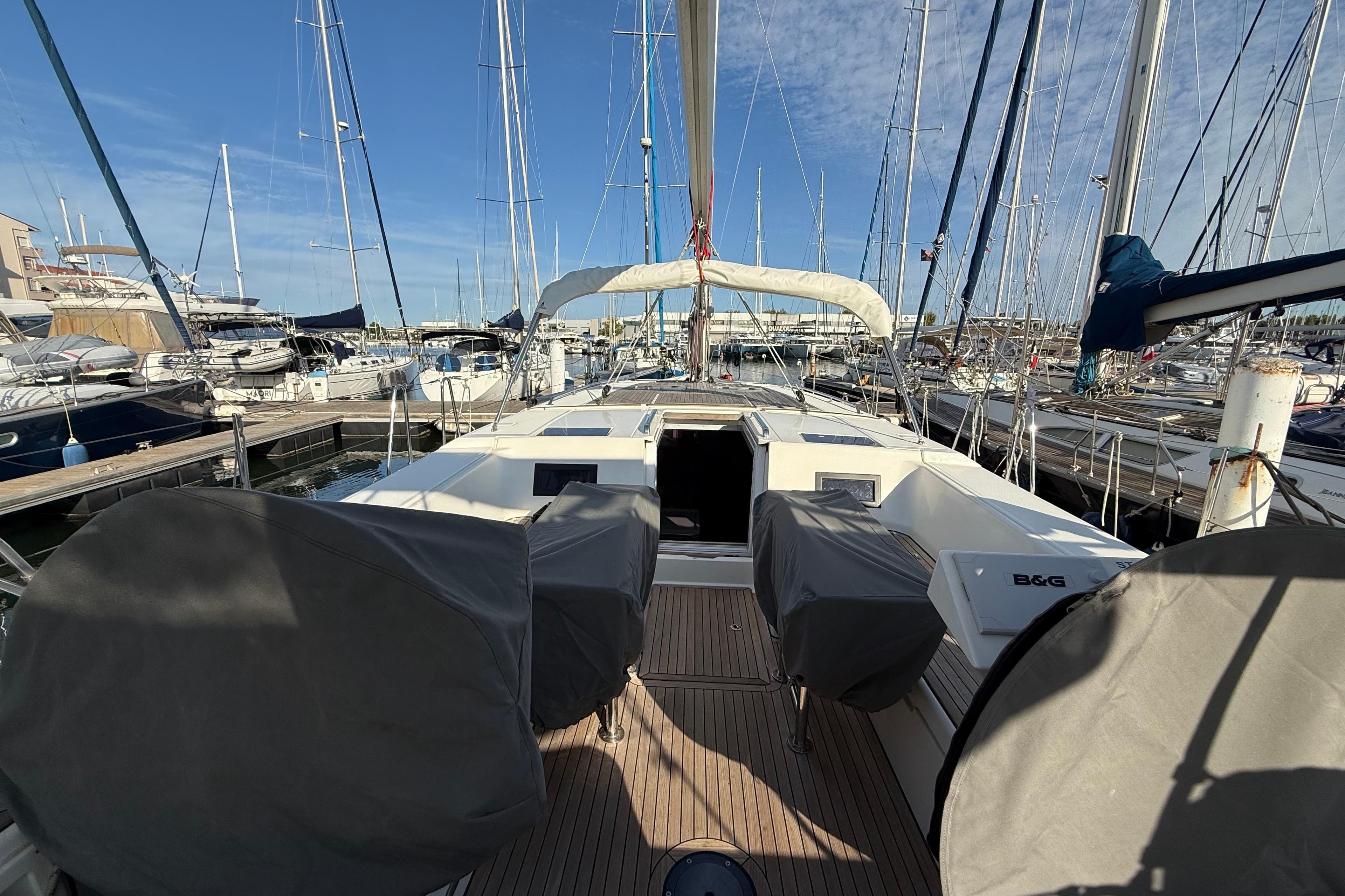 2019 Bavaria C45 yacht docked at marina, featuring covered steering wheels and spacious deck.