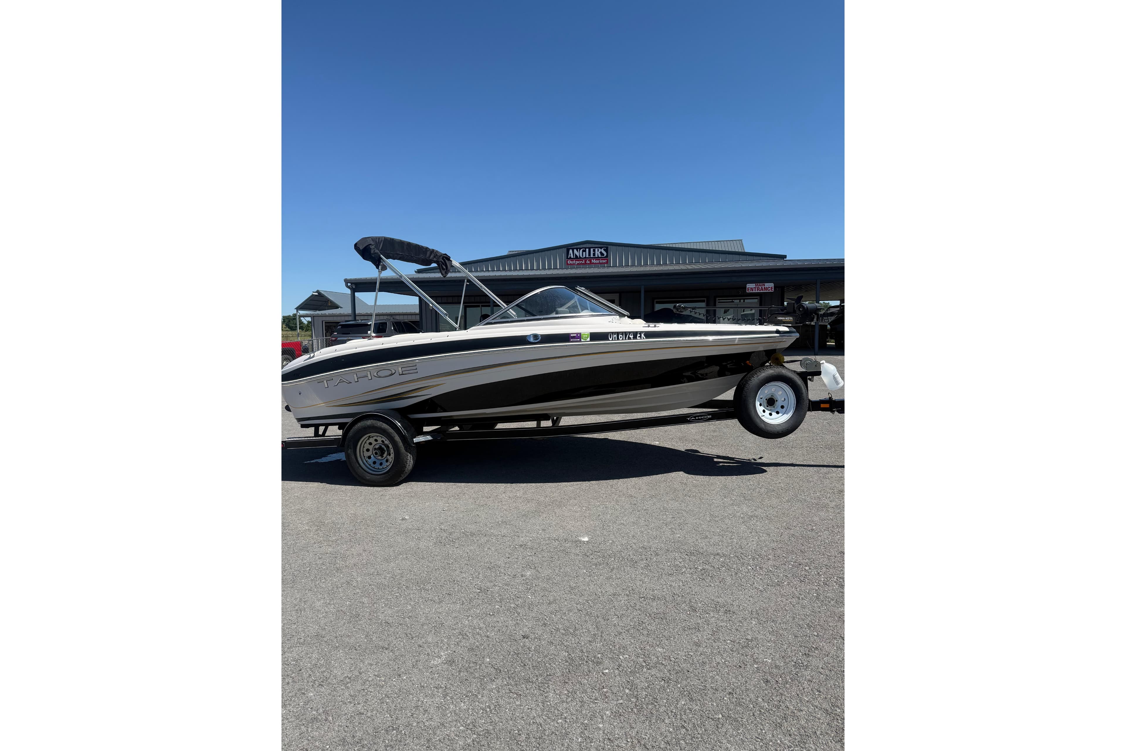 2008 Tahoe Q5i Sport boat on trailer, parked outdoors under clear blue sky.
