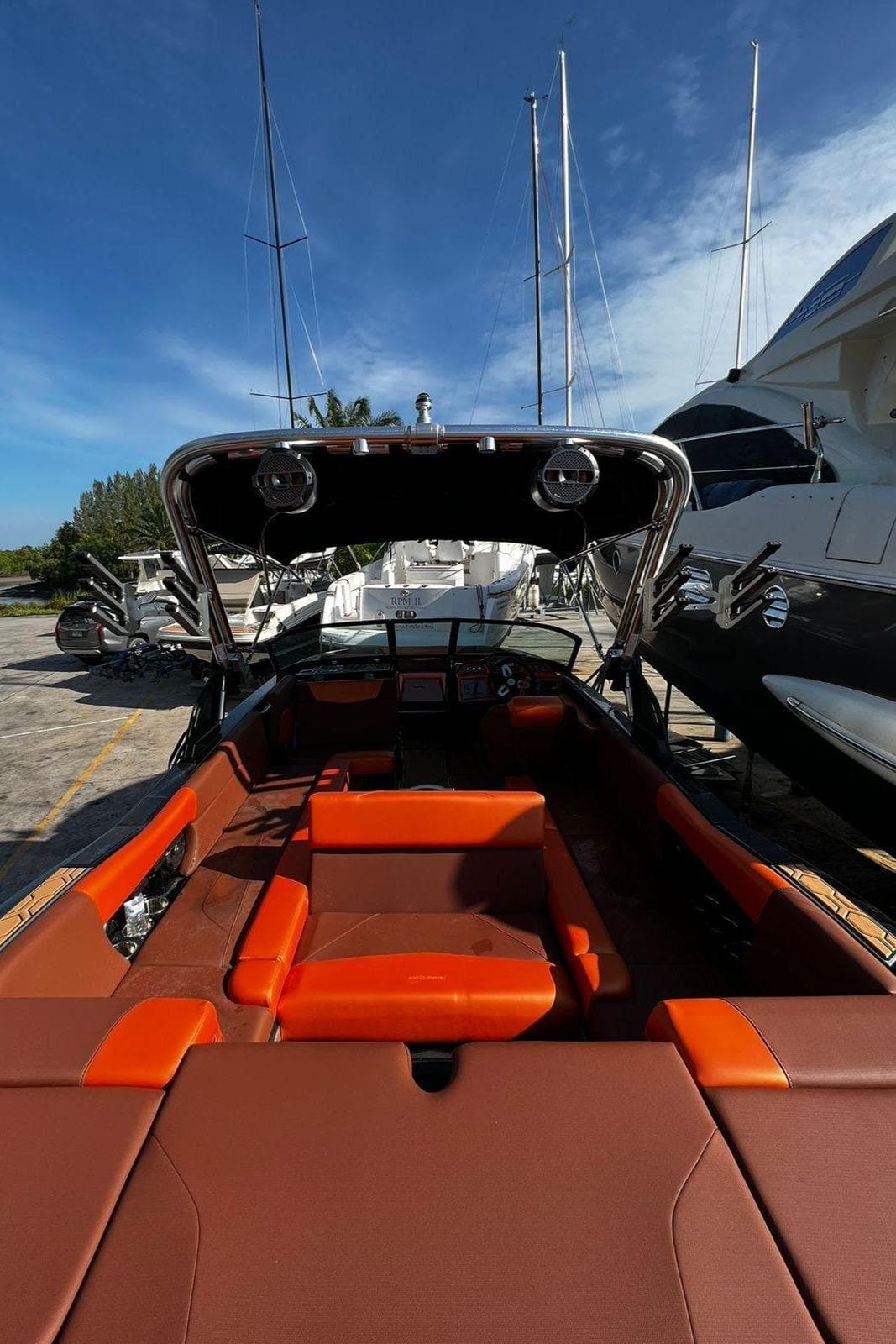 2022 MasterCraft NXT22 boat with orange interior, docked under clear blue sky.
