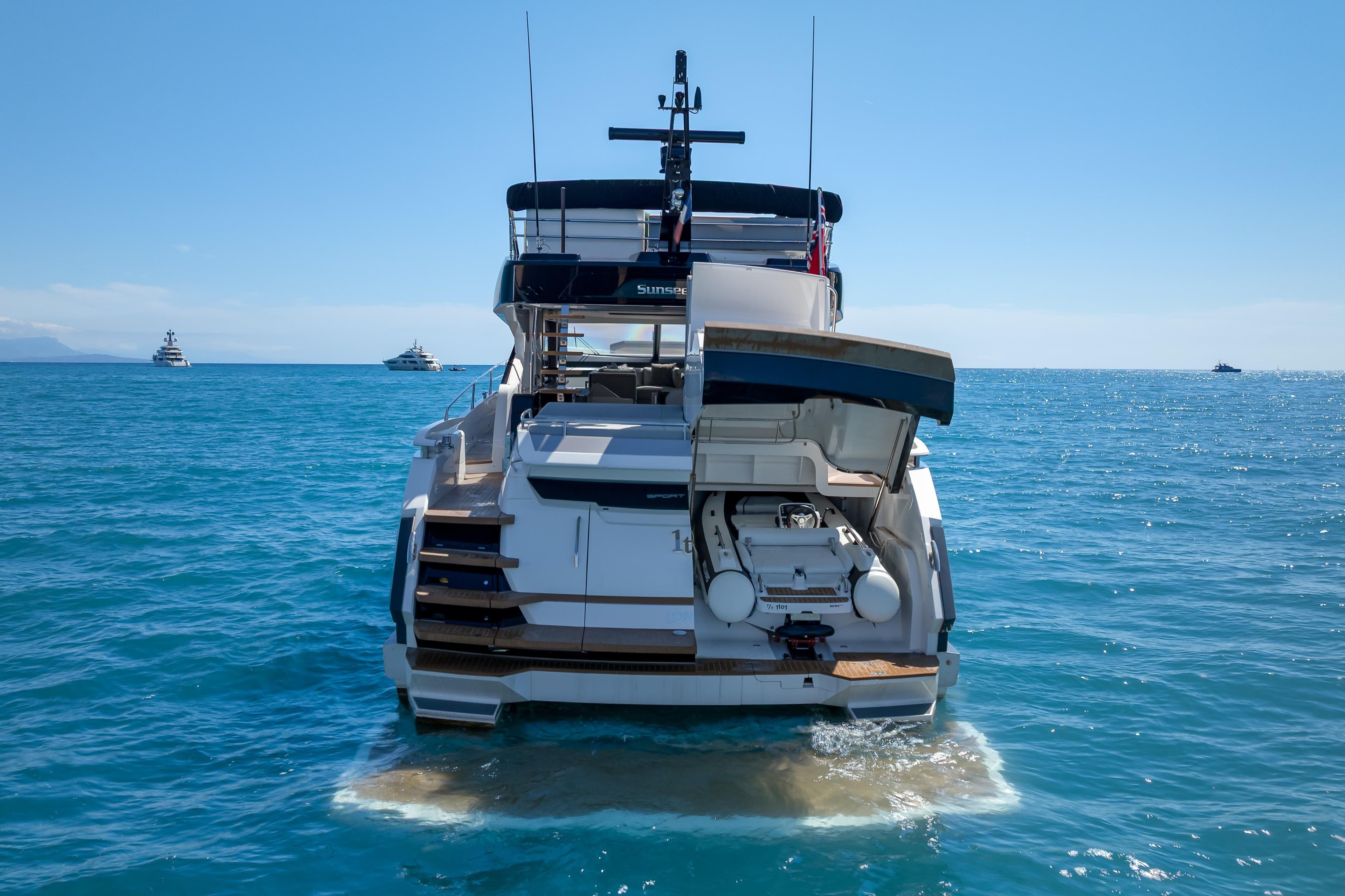 2024 Sunseeker 75 Sport Yacht on open sea, rear view with tender garage open.