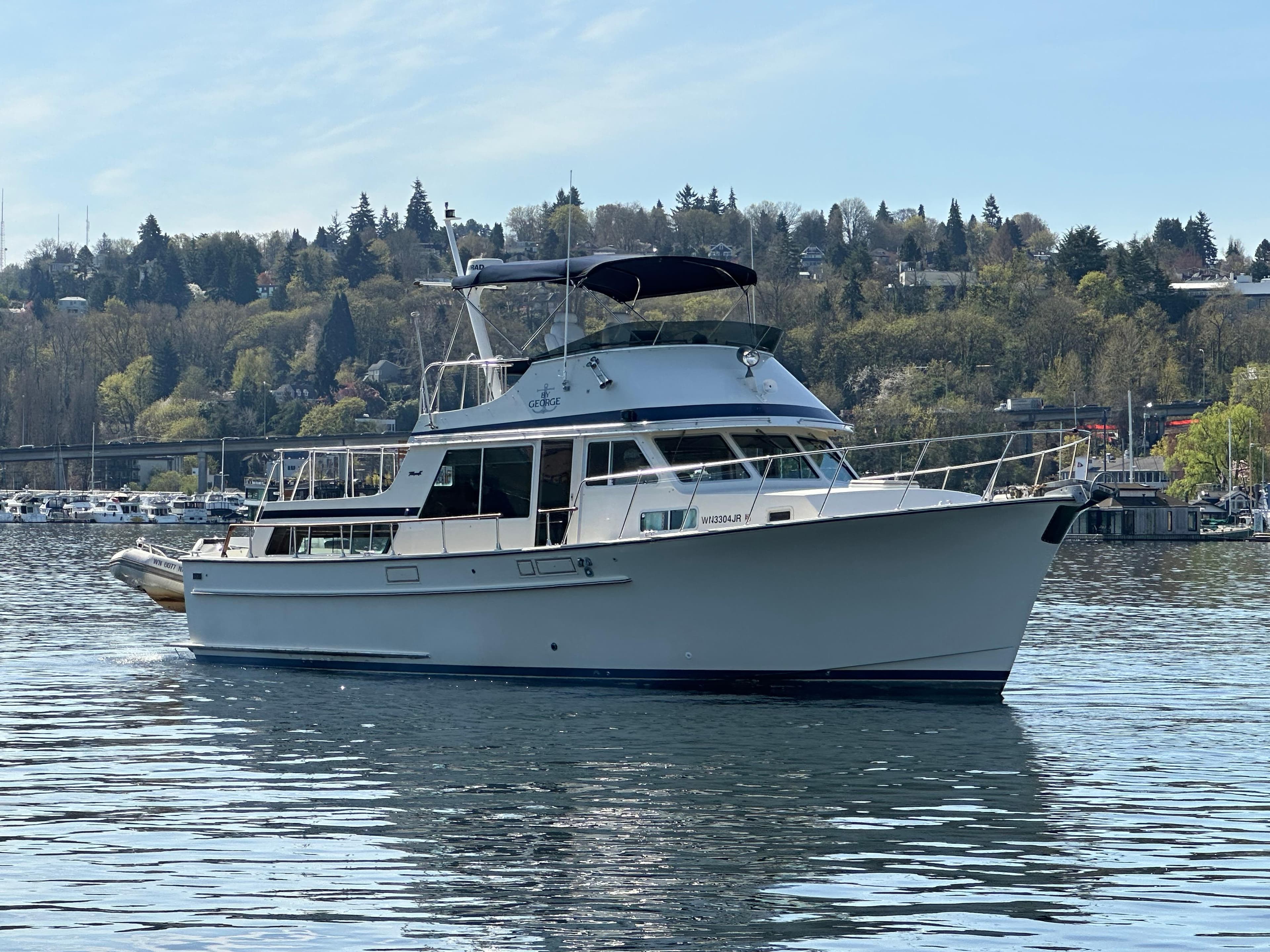 1982 Tollycraft Tri Cabin yacht on a serene lake with a wooded shoreline.