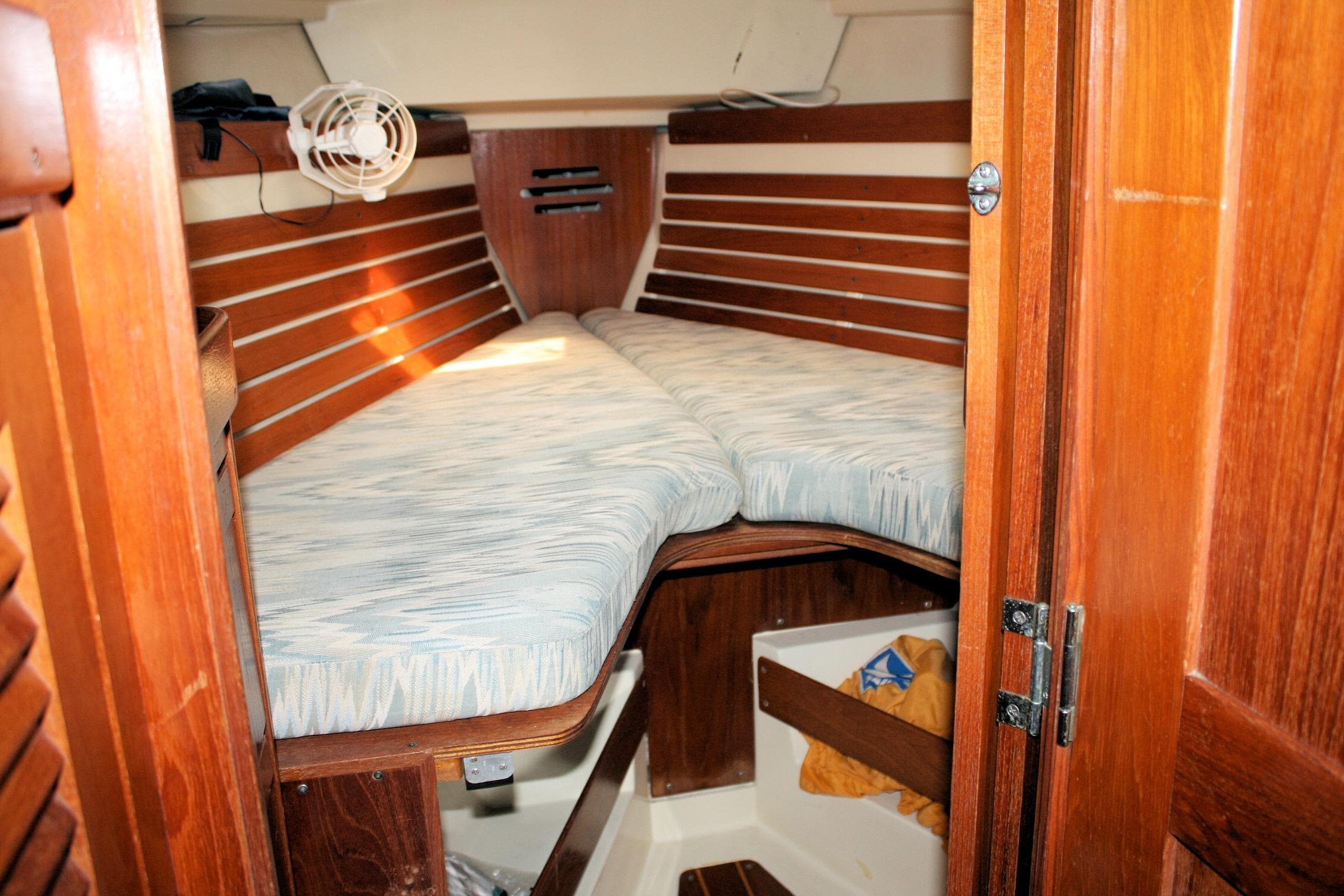 Cozy cabin interior of 1988 Pearson 31 sailboat with wooden finish and cushioned berth.
