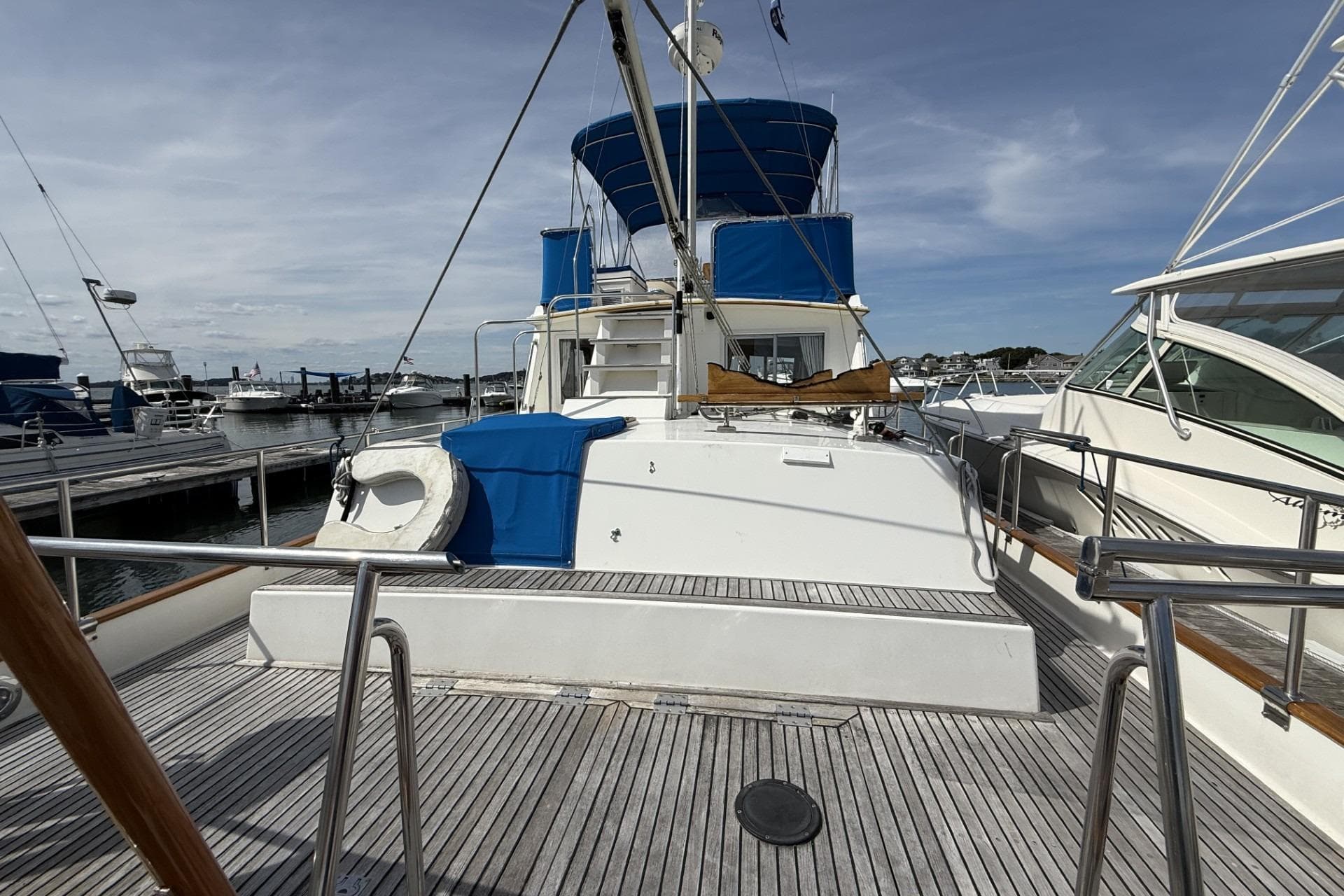 1999 Grand Banks 42 Classic yacht docked at marina, featuring blue canopy and wooden deck.