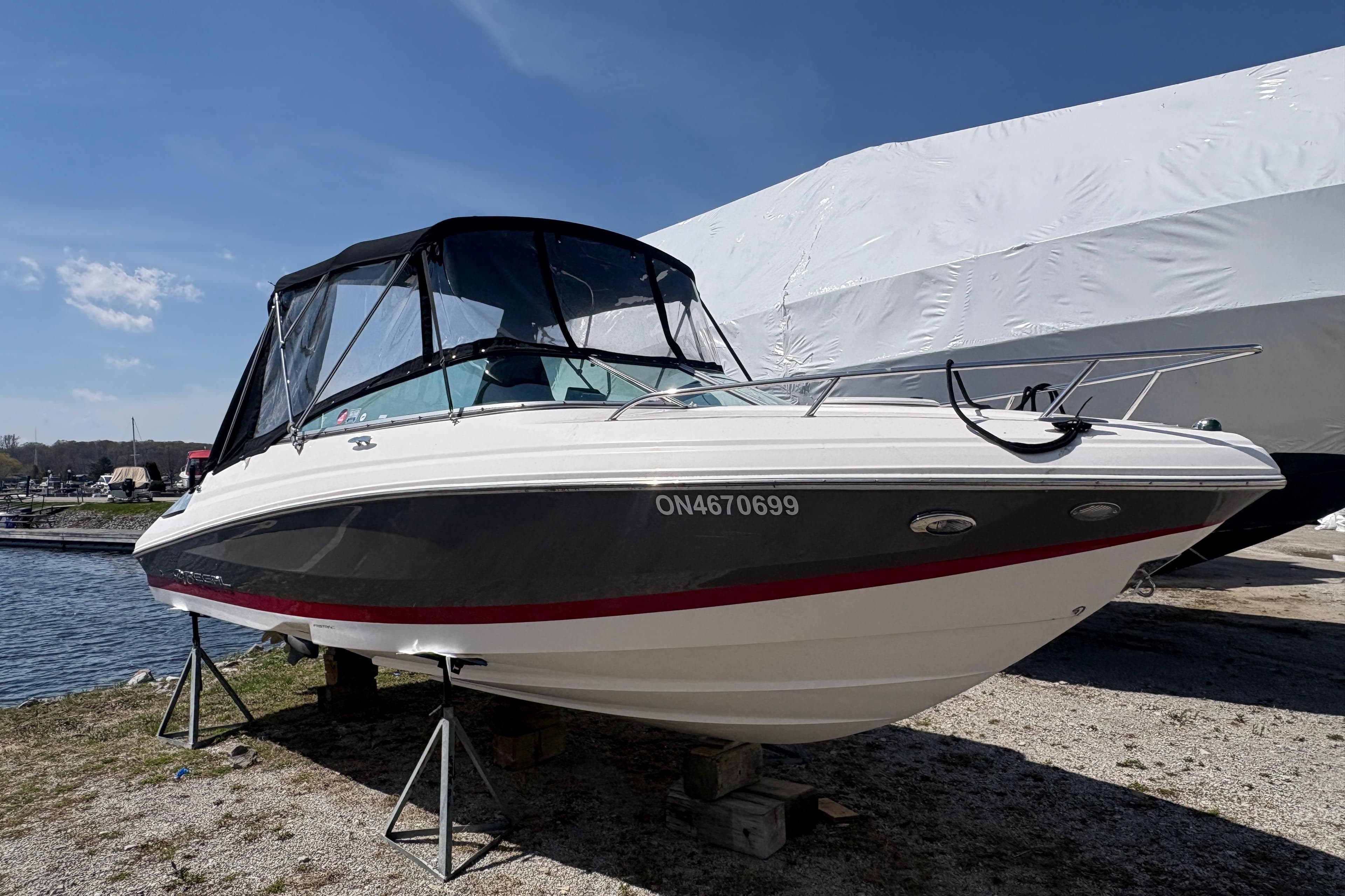 2015 Regal 2250 Cuddy boat on stands by the water, under a clear sky.