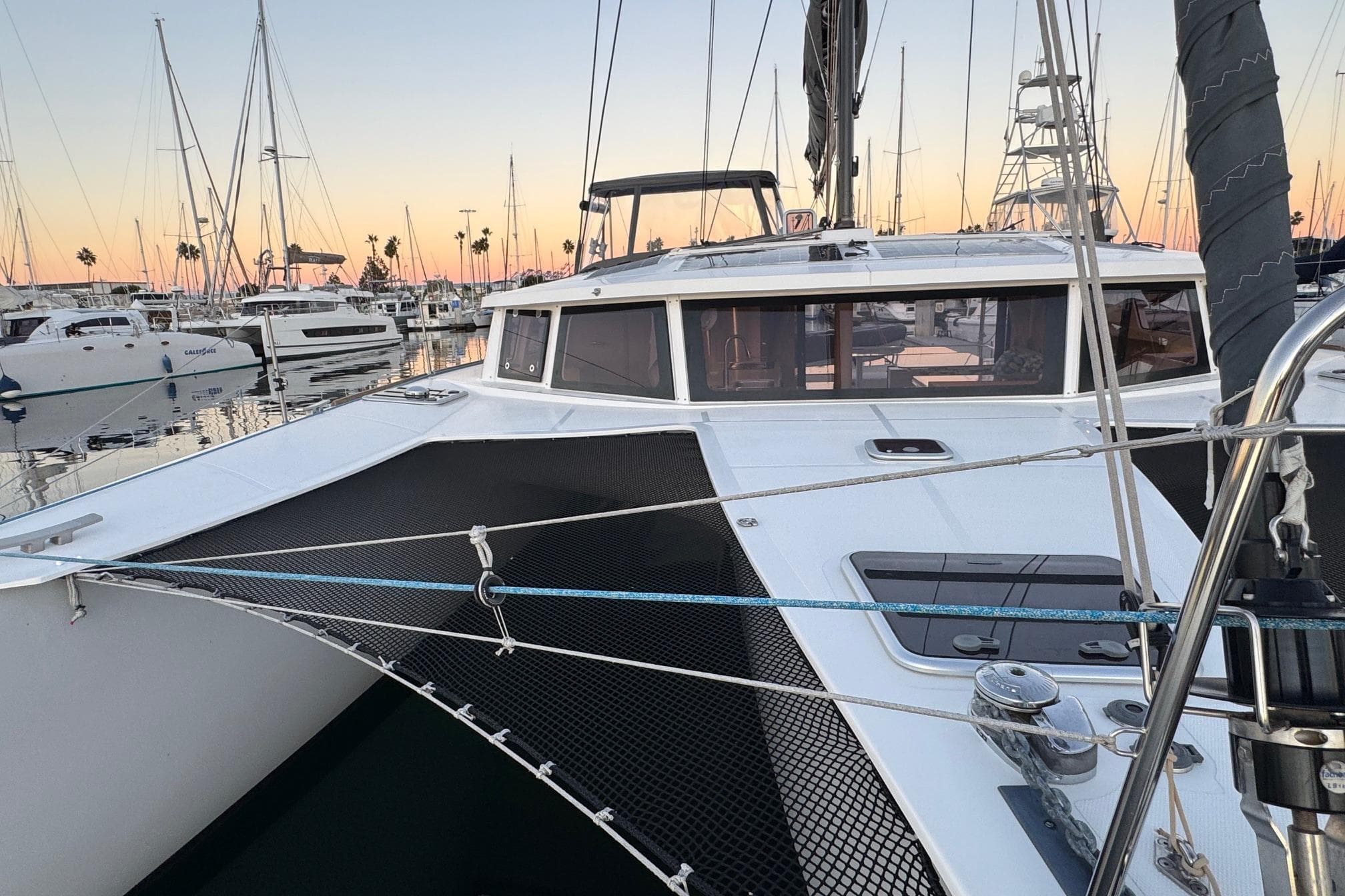 2023 NEEL 43 trimaran docked at marina during sunset, surrounded by sailboats.