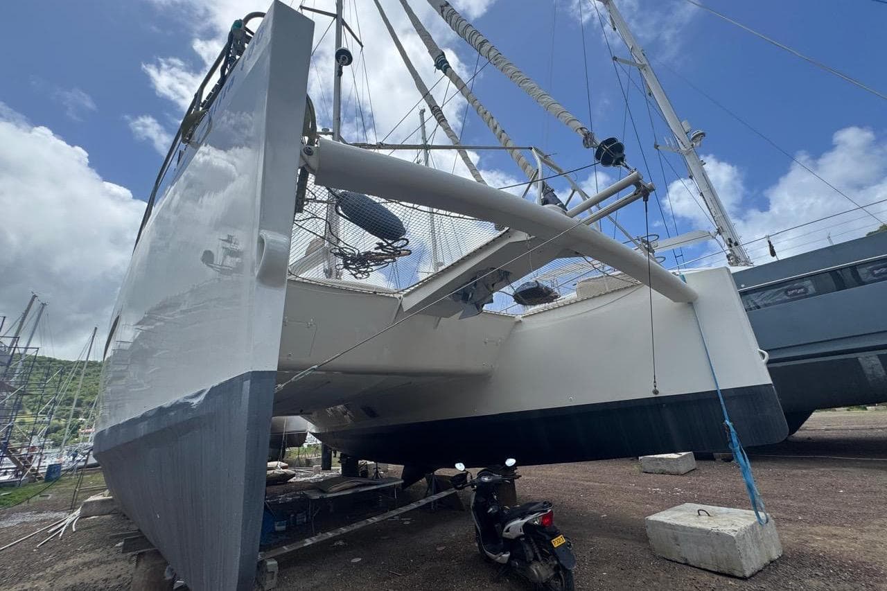 Custom COAST 50 catamaran, 2018 model, docked on land with clear blue sky.