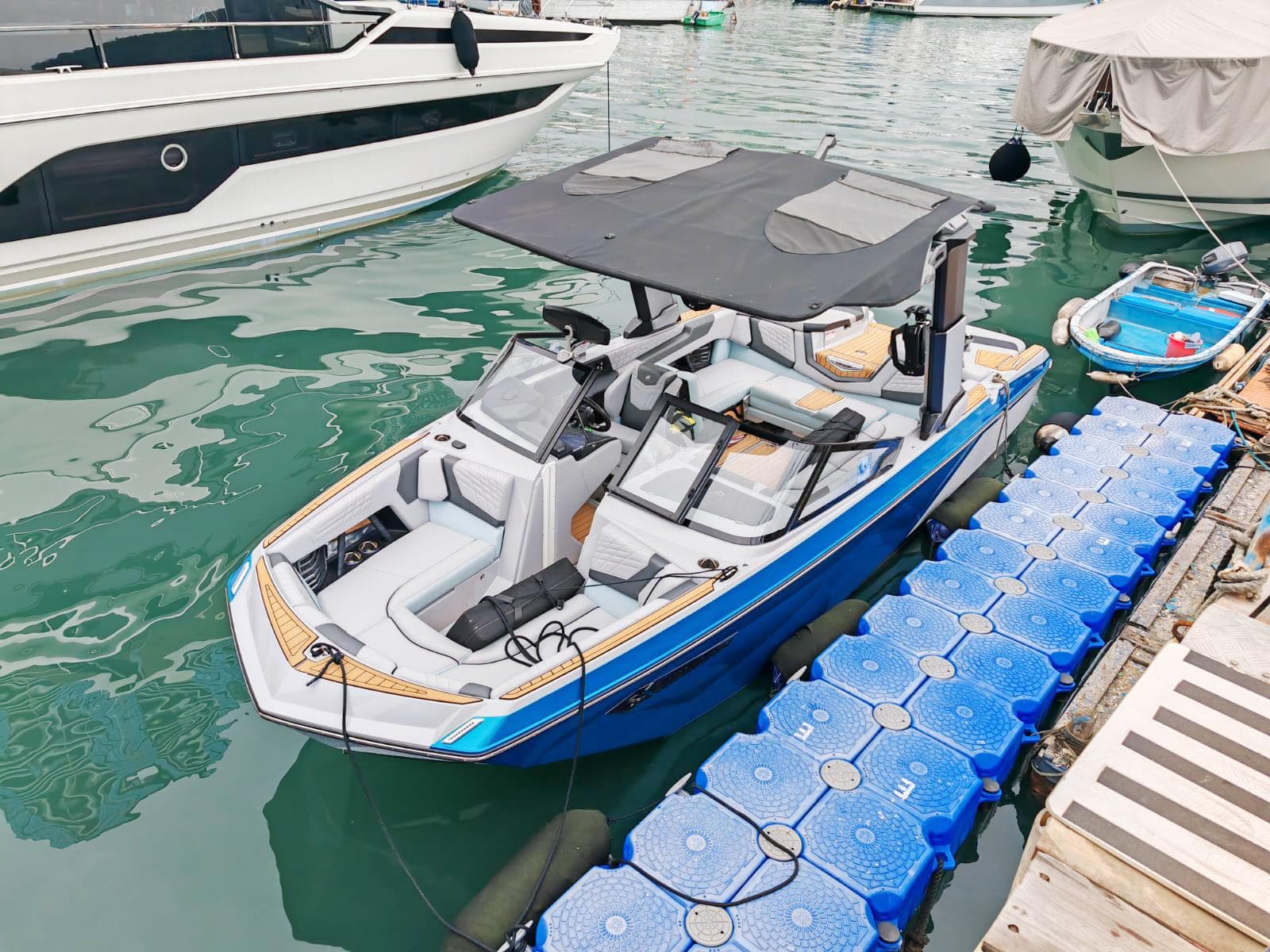 2022 Nautique Super Air Nautique G23 boat docked in marina, featuring sleek design and canopy.