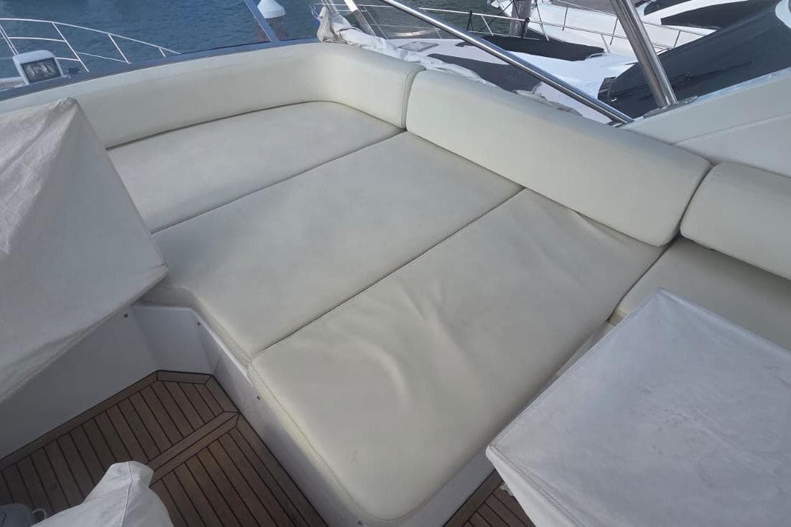 Luxurious seating area on 2015 Azimut 54 yacht with white cushions and wooden deck.