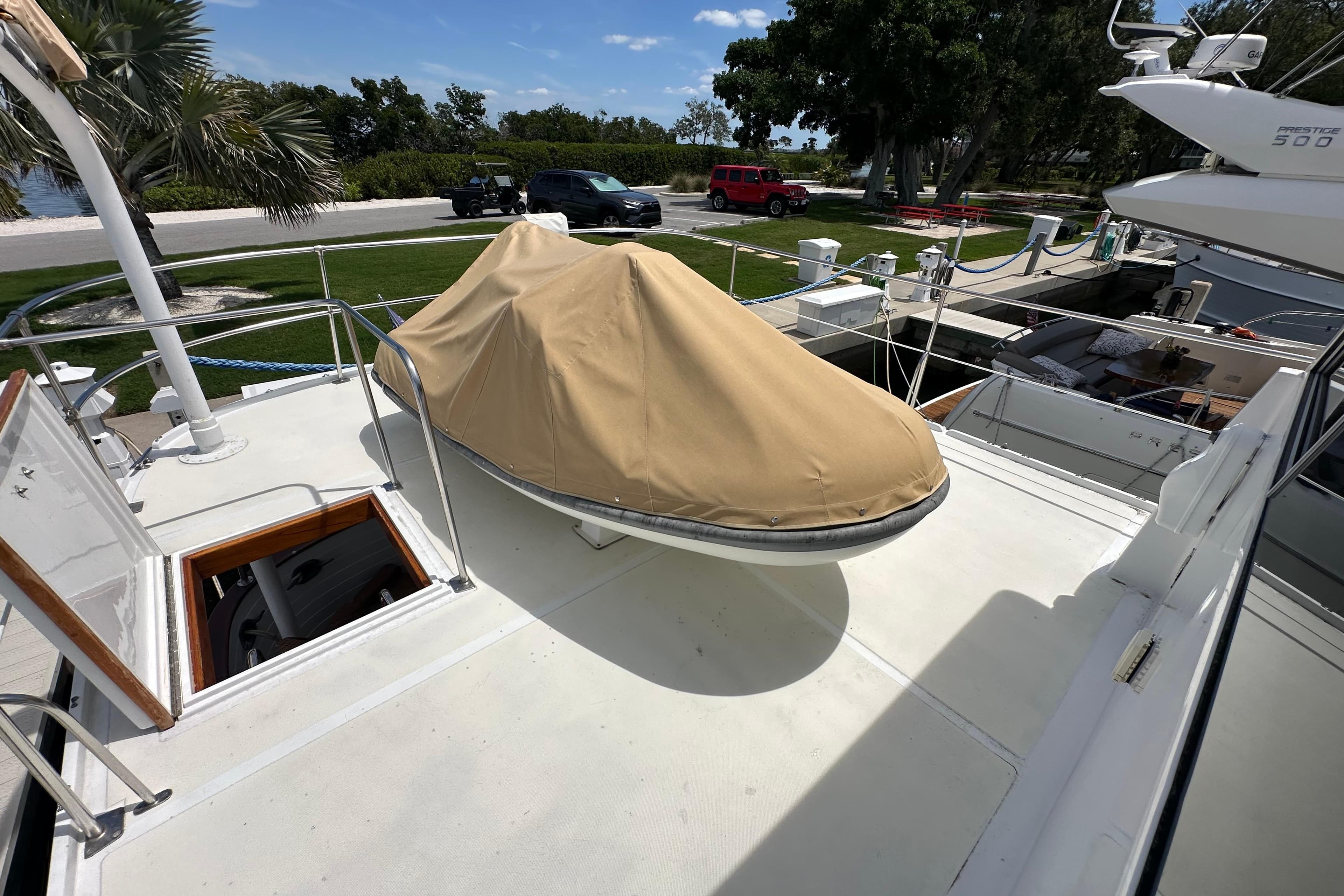 1987 Kadey-Krogen Manatee 36 yacht deck with covered equipment, docked near lush greenery.