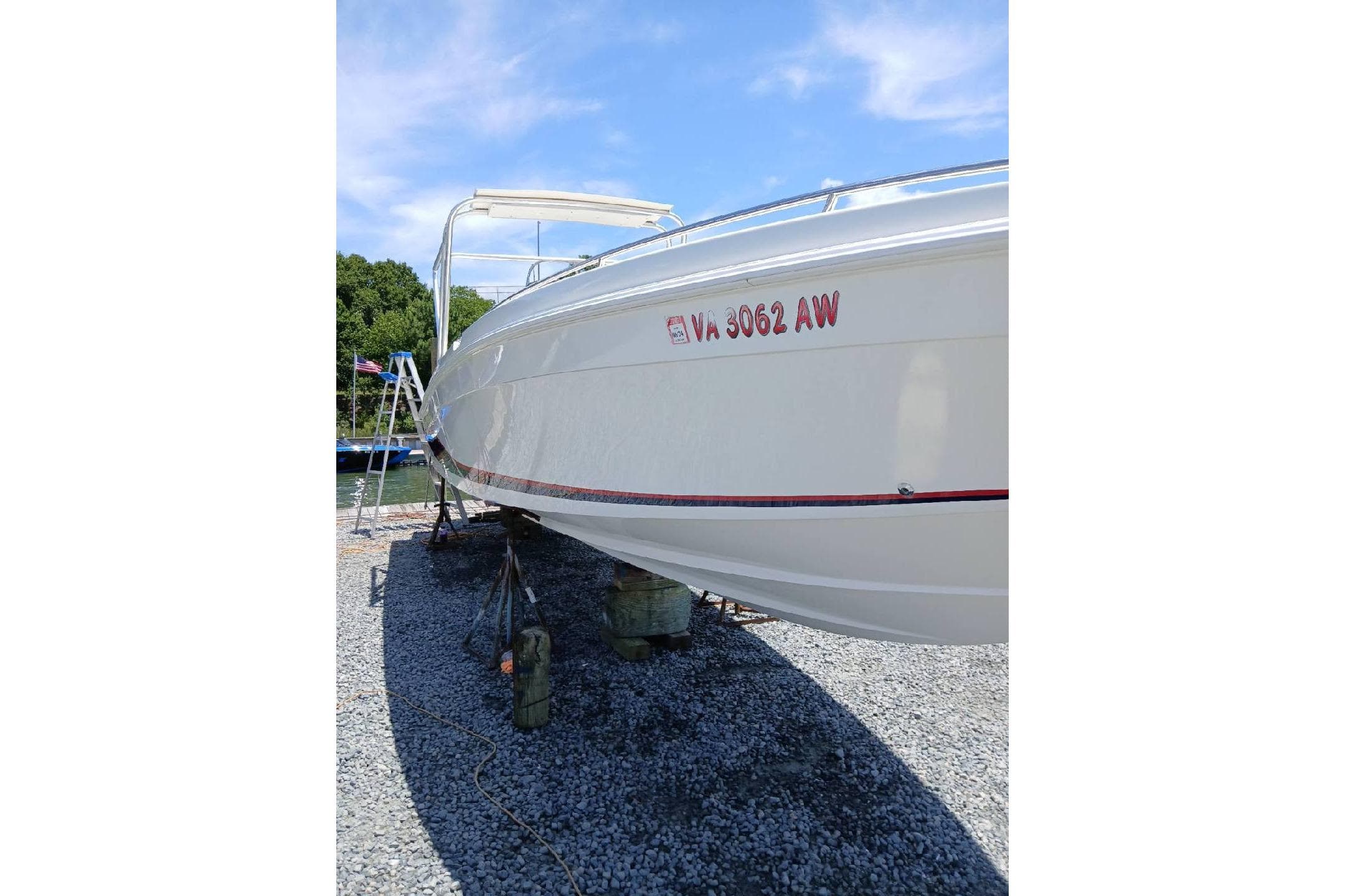 1999 Wellcraft Scarab 302 Sport boat on gravel, side view with registration number visible.