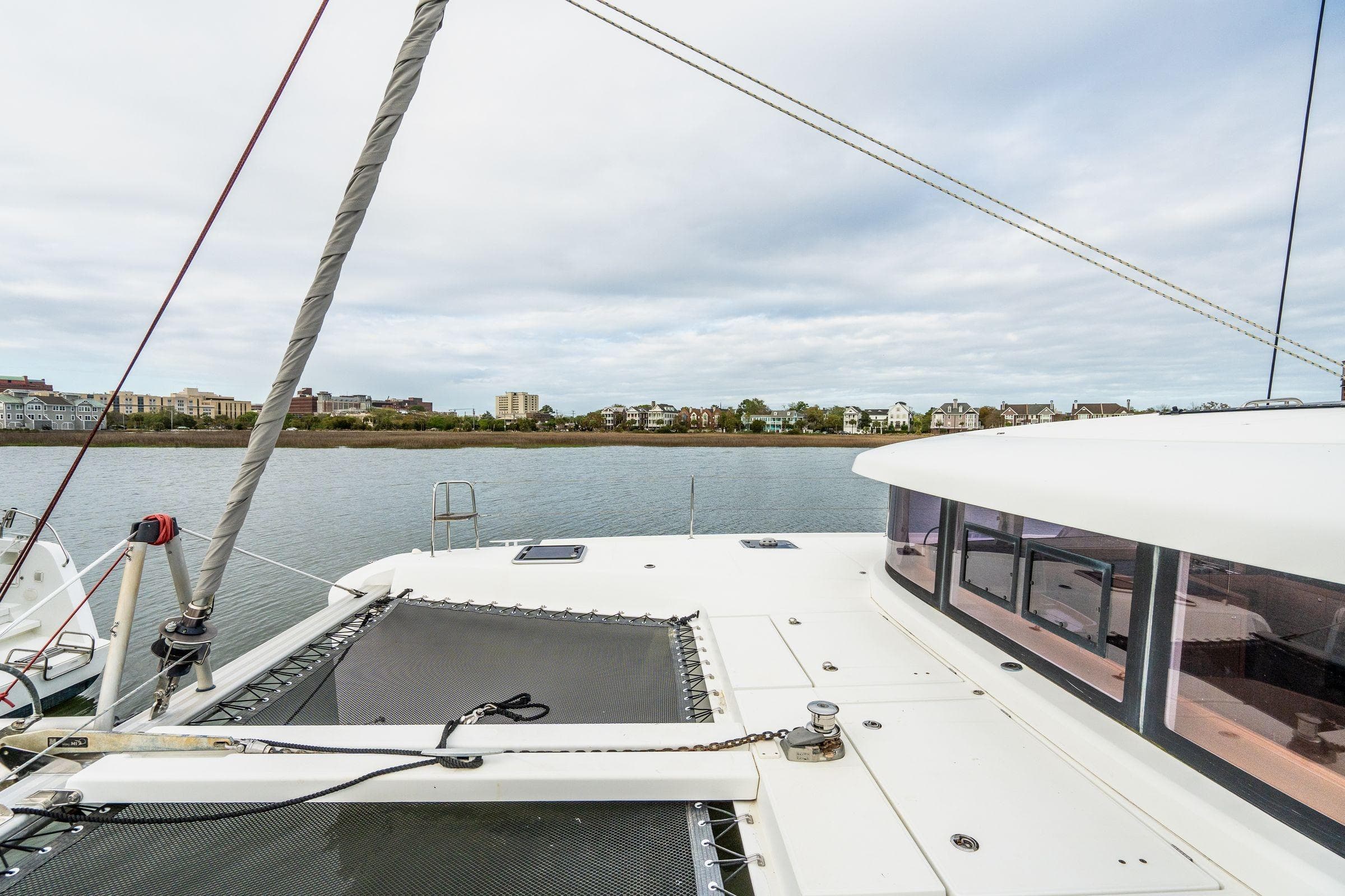 2017 Lagoon 42 catamaran deck view with coastal backdrop and overcast sky.
