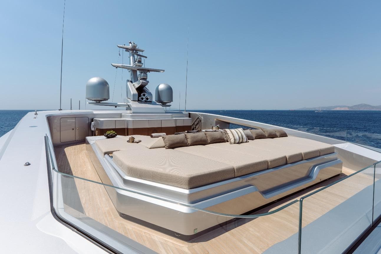 Luxurious 2024 Tecnomar Custom yacht deck with sunbed, overlooking serene ocean view.