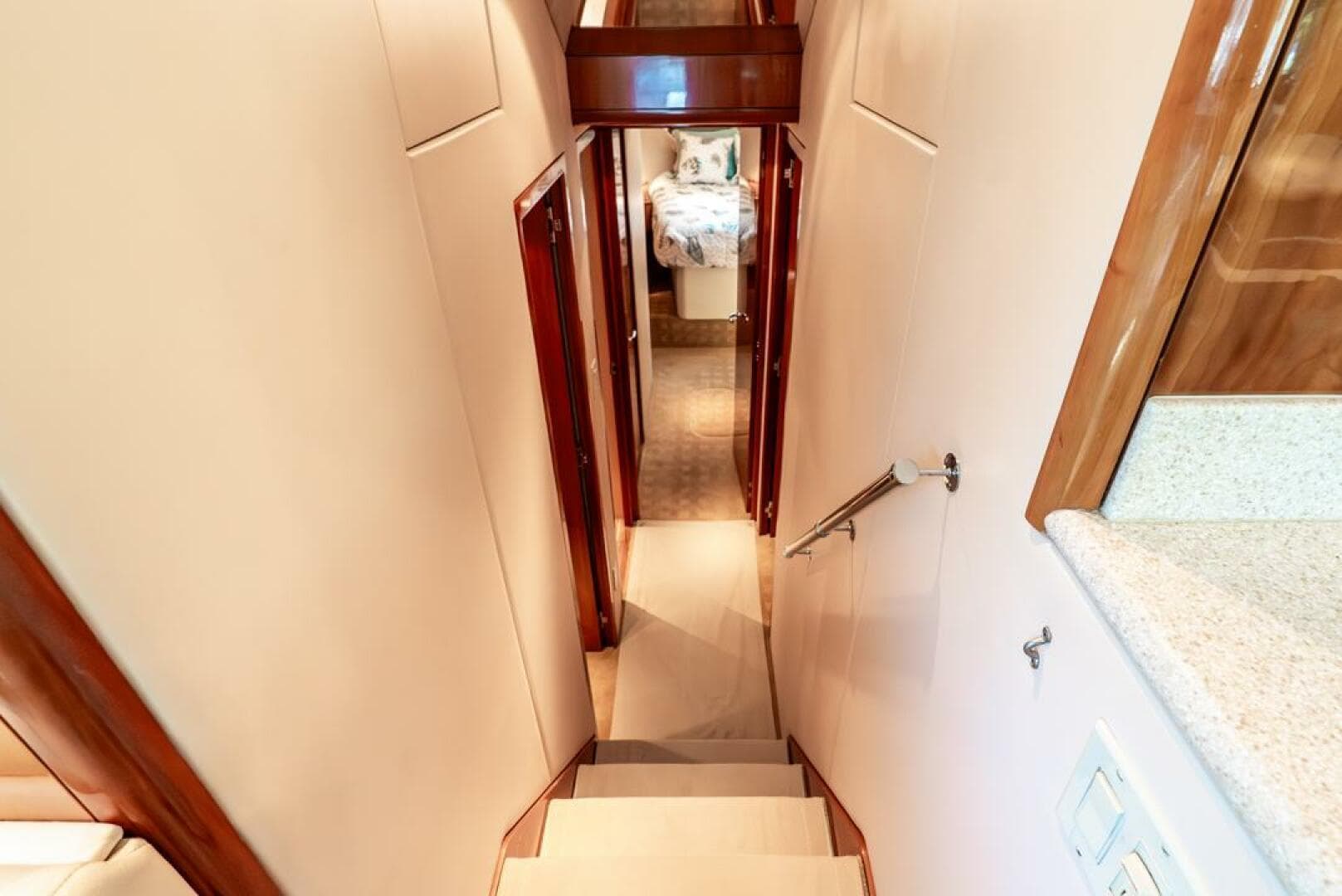 Interior hallway of 2005 Hatteras 50 Convertible Sportfish yacht, featuring wooden accents and carpeted stairs.