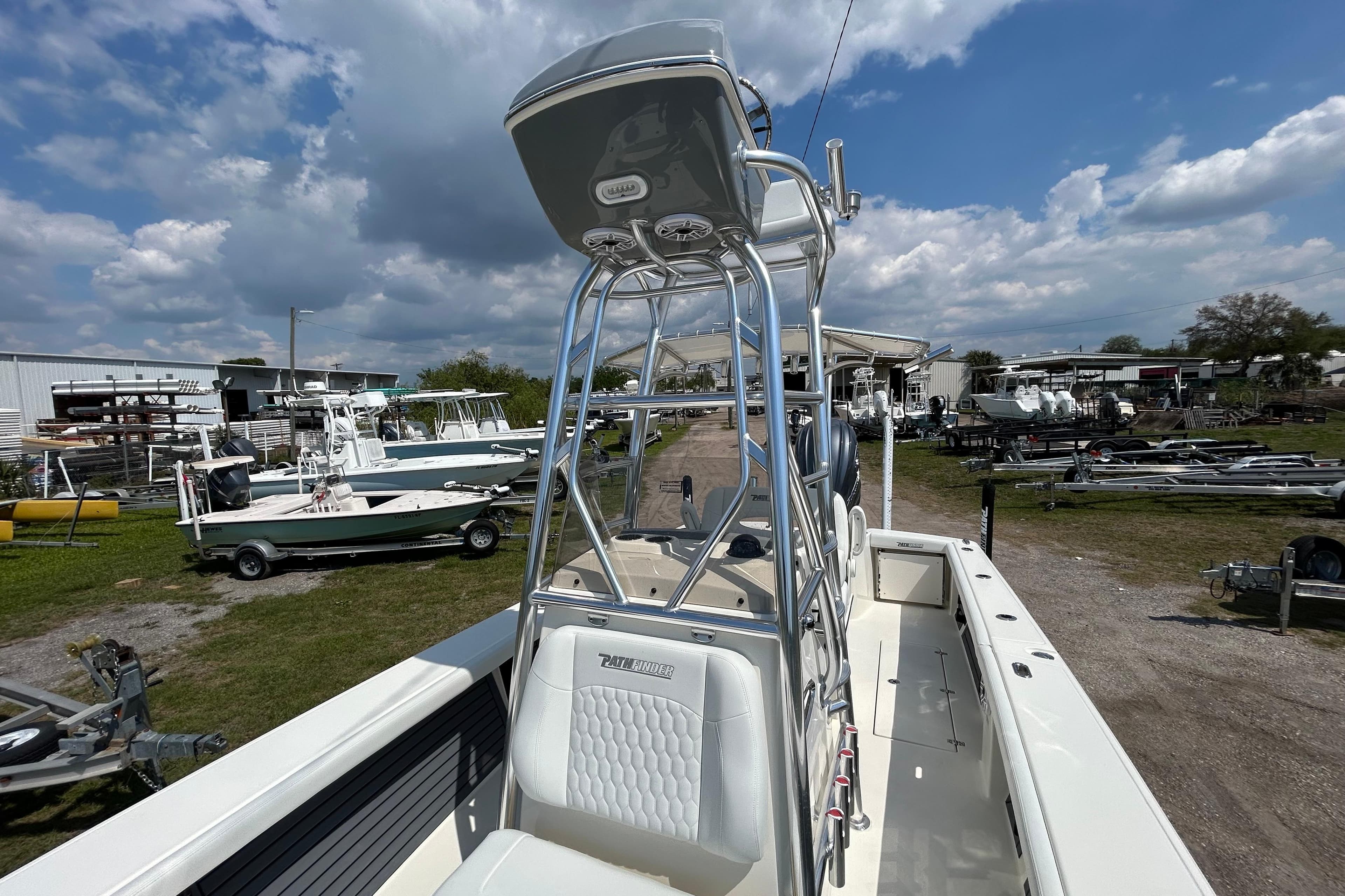 2026 Pathfinder 2700 Open boat with T-top, parked outdoors under a cloudy sky.