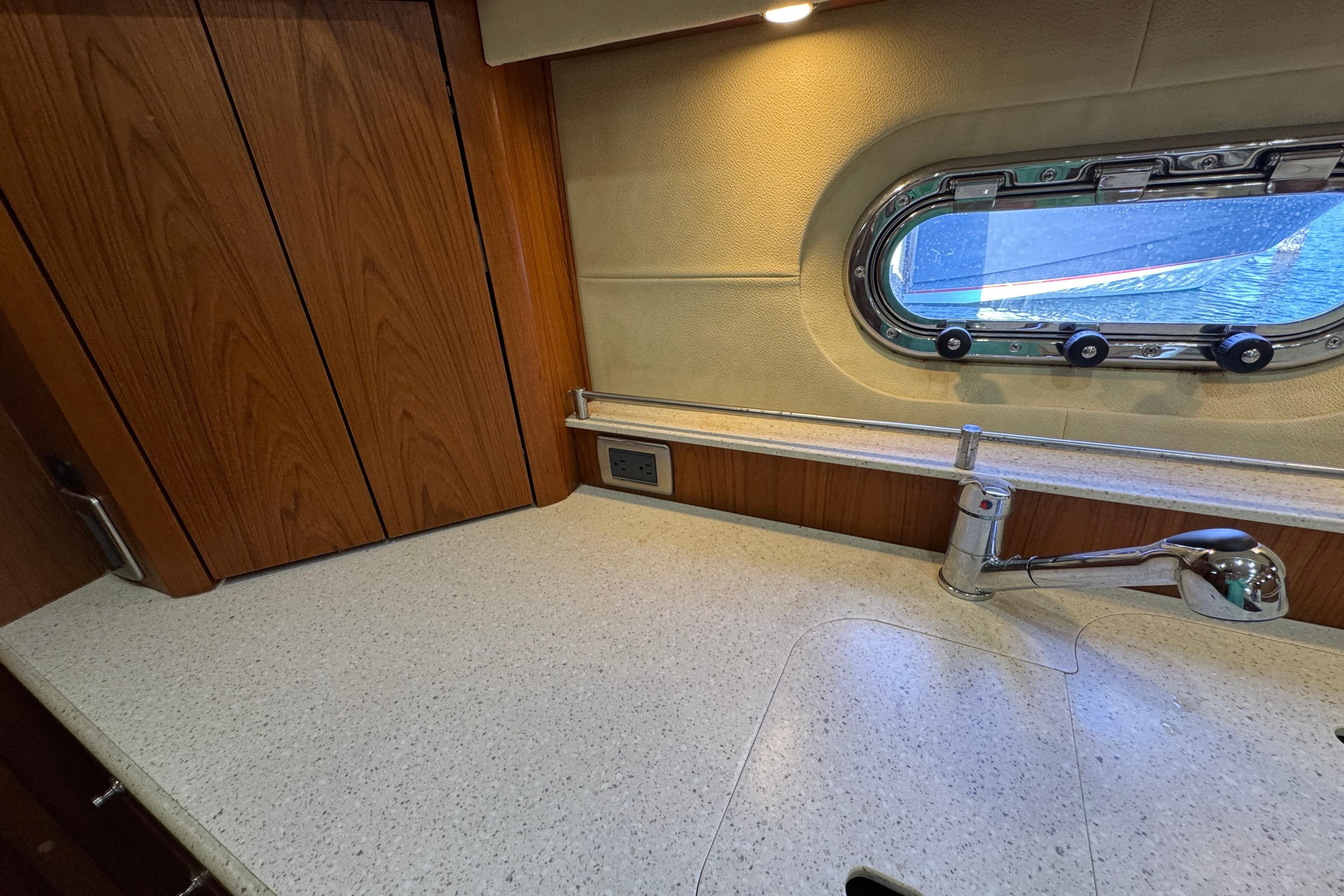 Tiara 43 yacht kitchen with wood cabinets, countertop, faucet, and porthole window, 2007 model.