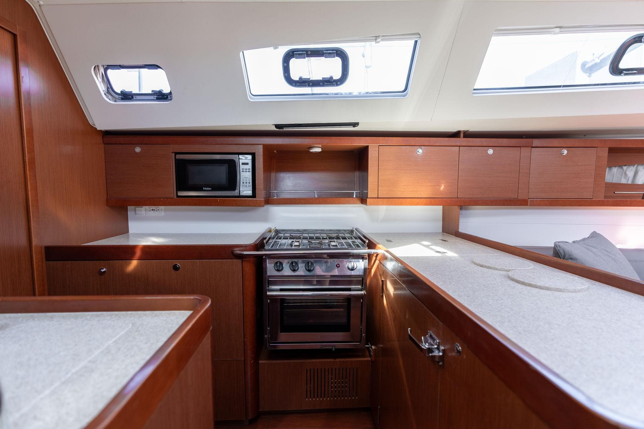 Interior of 2013 Beneteau Oceanis 50 yacht kitchen with stove, microwave, and wooden cabinetry.