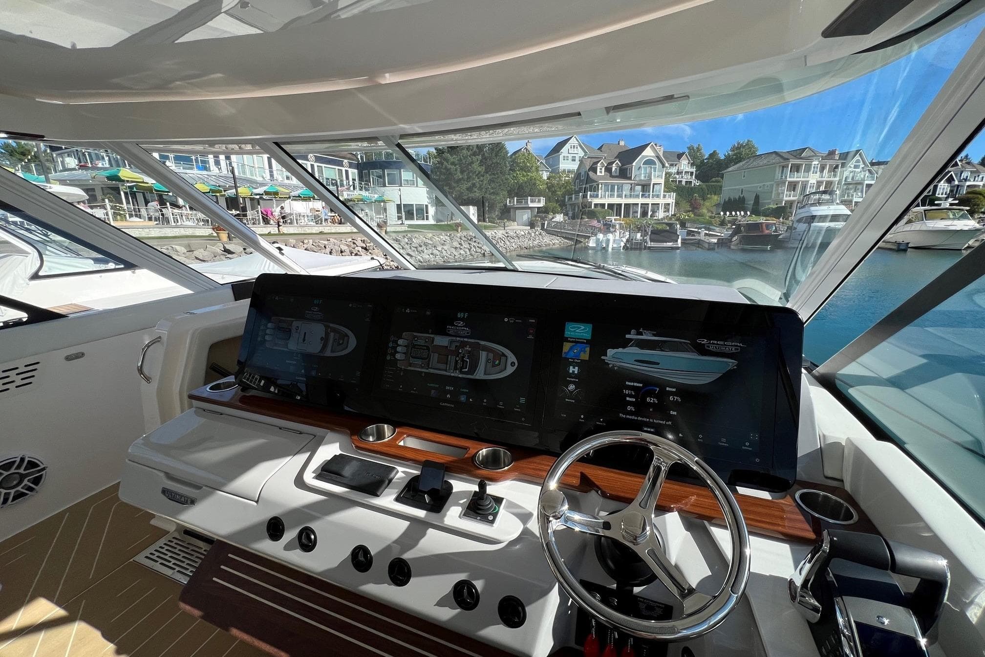 Helm of 2026 Regal LX43 yacht with advanced navigation screens, docked in a scenic marina.