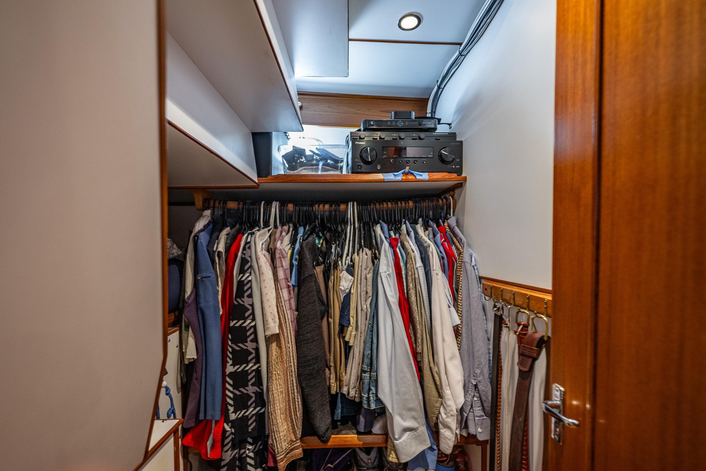 Closet with clothes and audio equipment in 2007 DeFever 56 yacht interior.