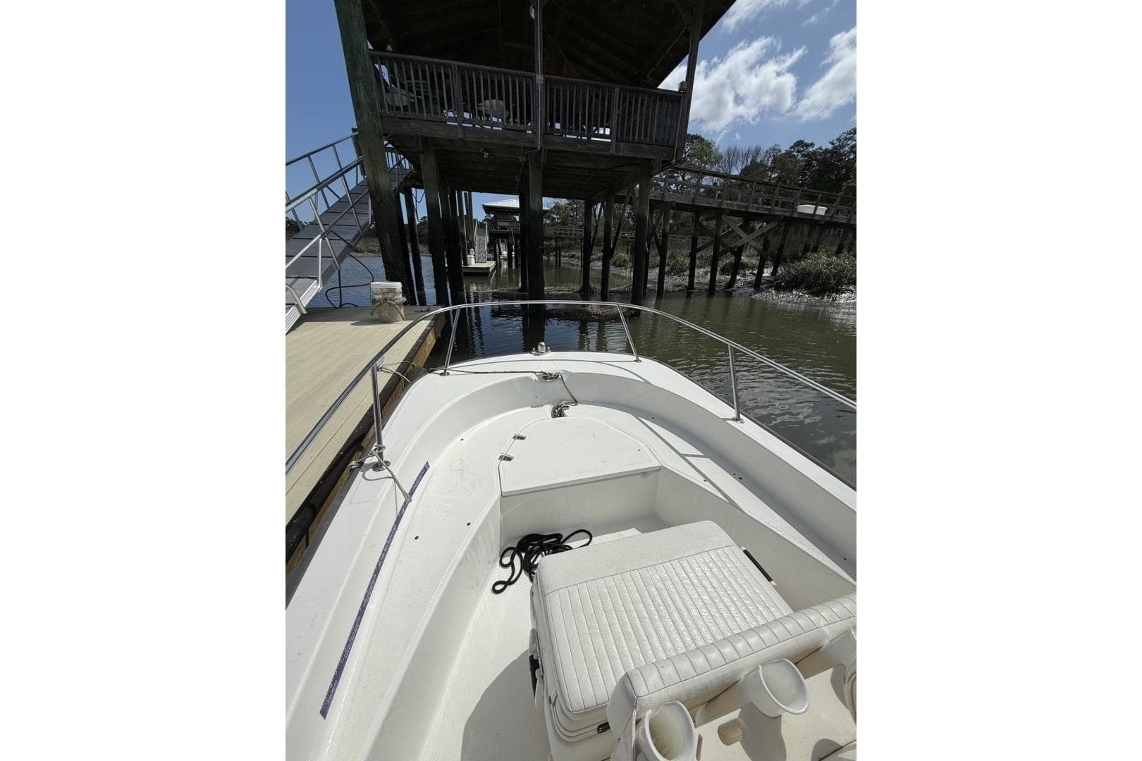 2016 Boston Whaler 170 Montauk boat docked near wooden pier under blue sky.