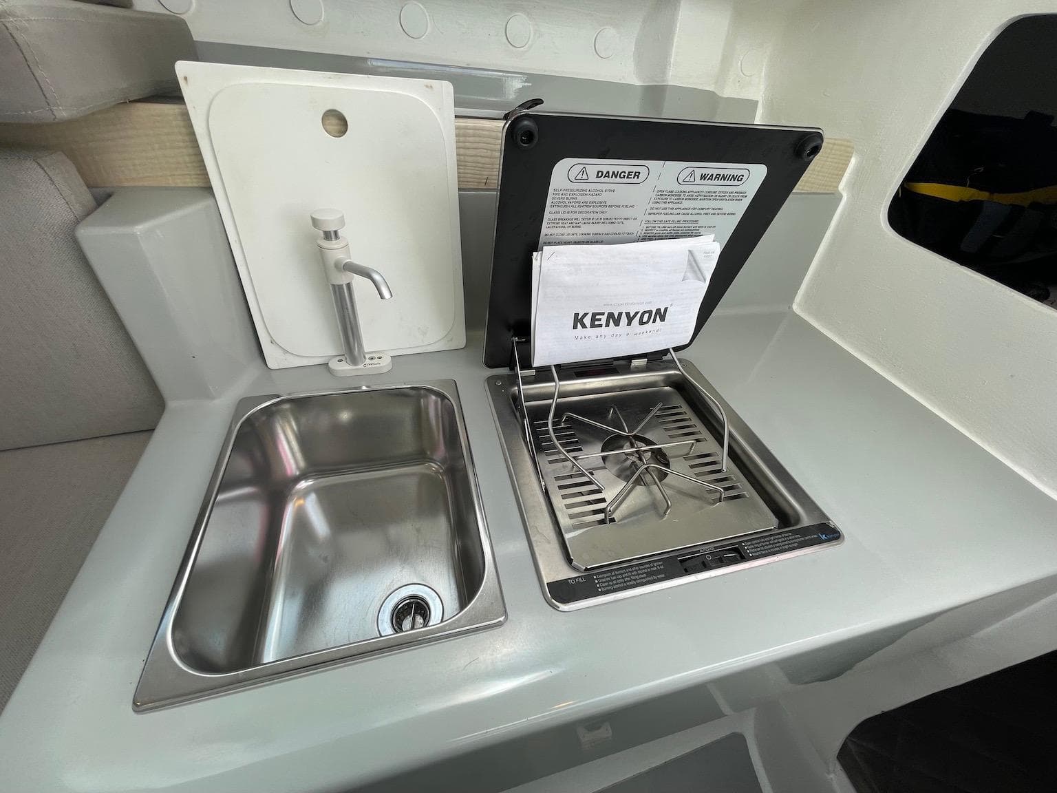 Compact kitchen area in a 2025 Corsair 880, featuring a sink and Kenyon stove.