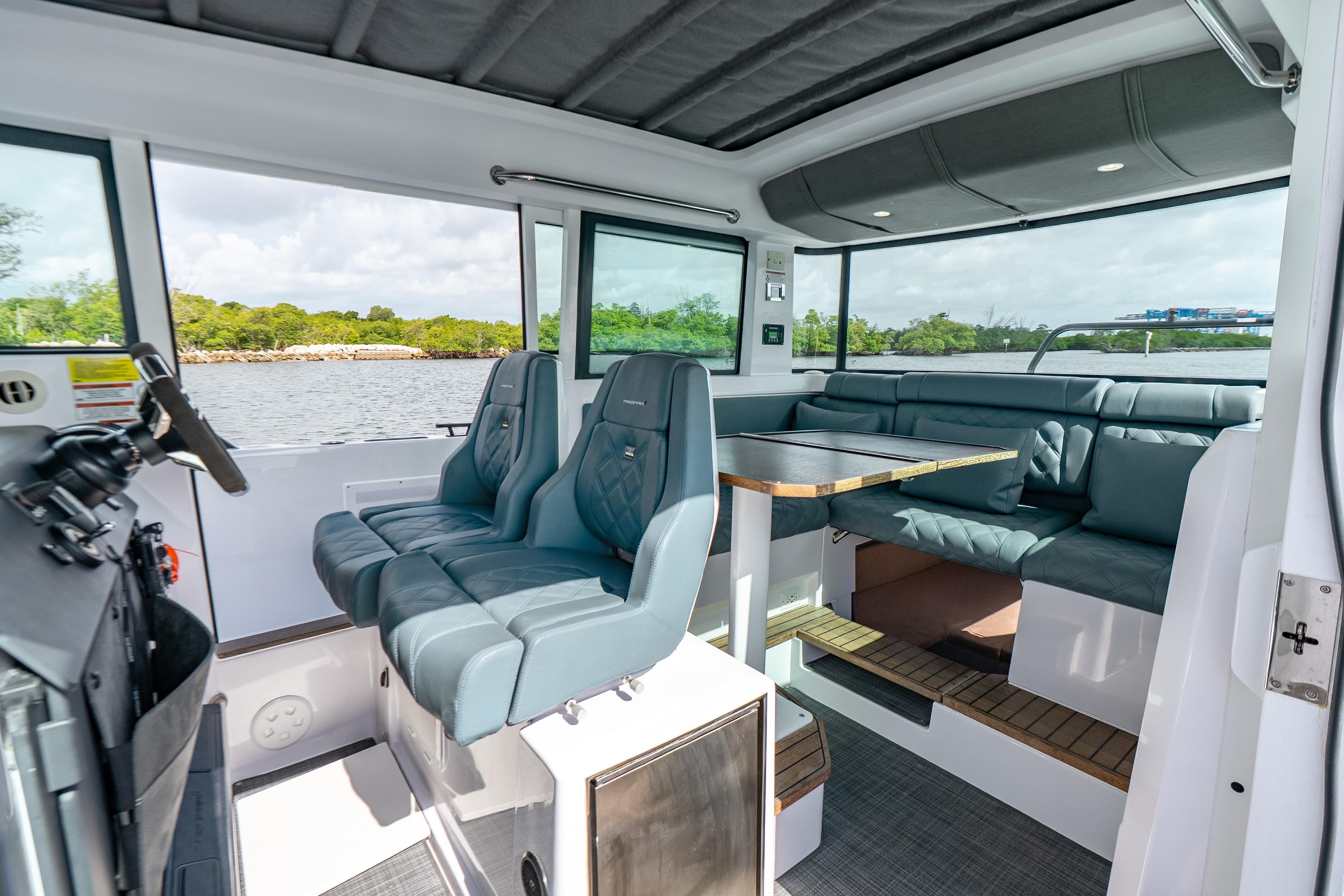 2022 Axopar 37 XC Cross Cabin interior with seating and table, overlooking water.