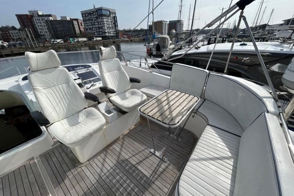Luxury seating area on 2005 Hardy Commodore 50 yacht, docked in a marina.