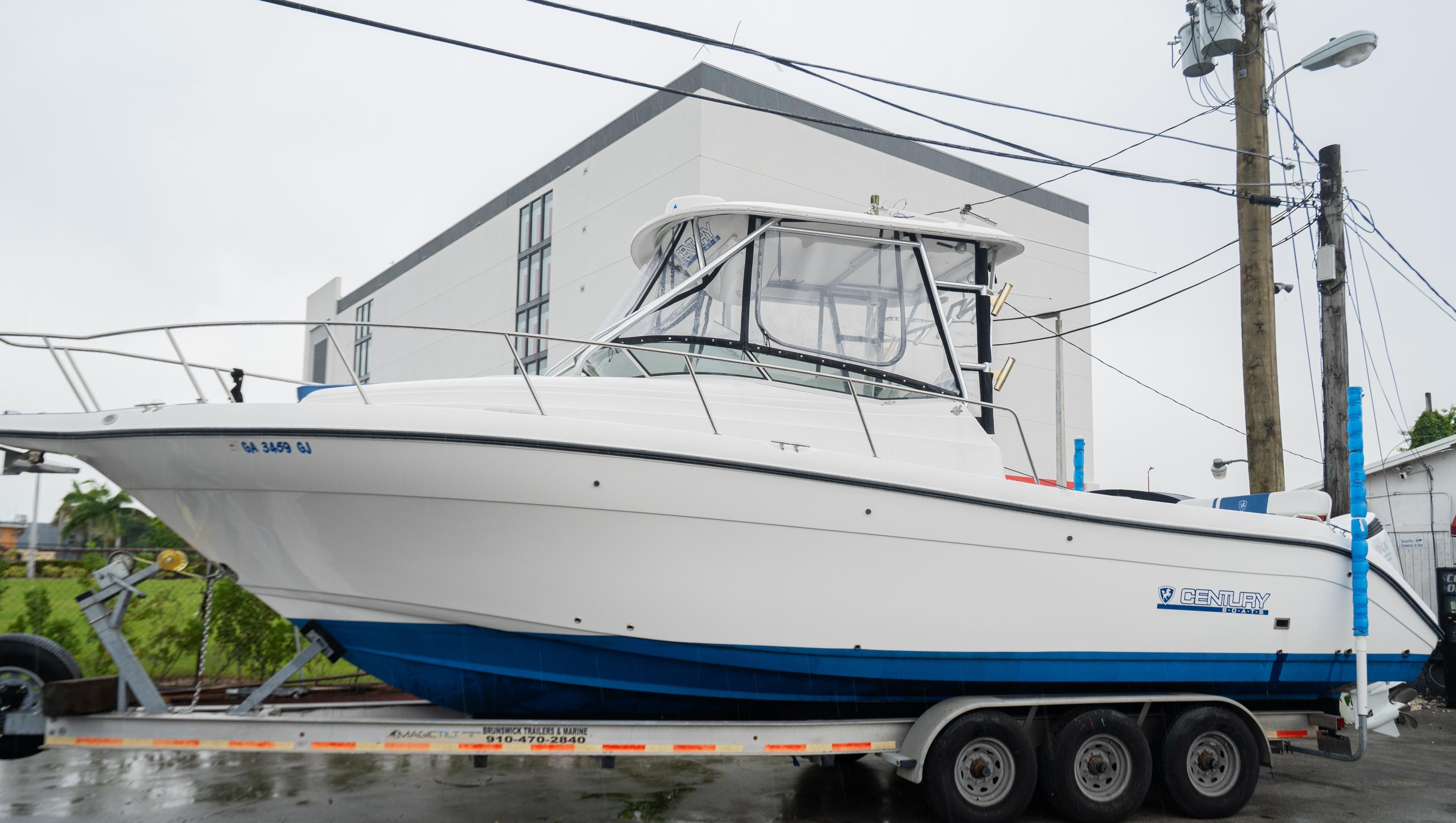 2002 Century 3200 Walk-Around boat on trailer, parked near a building.