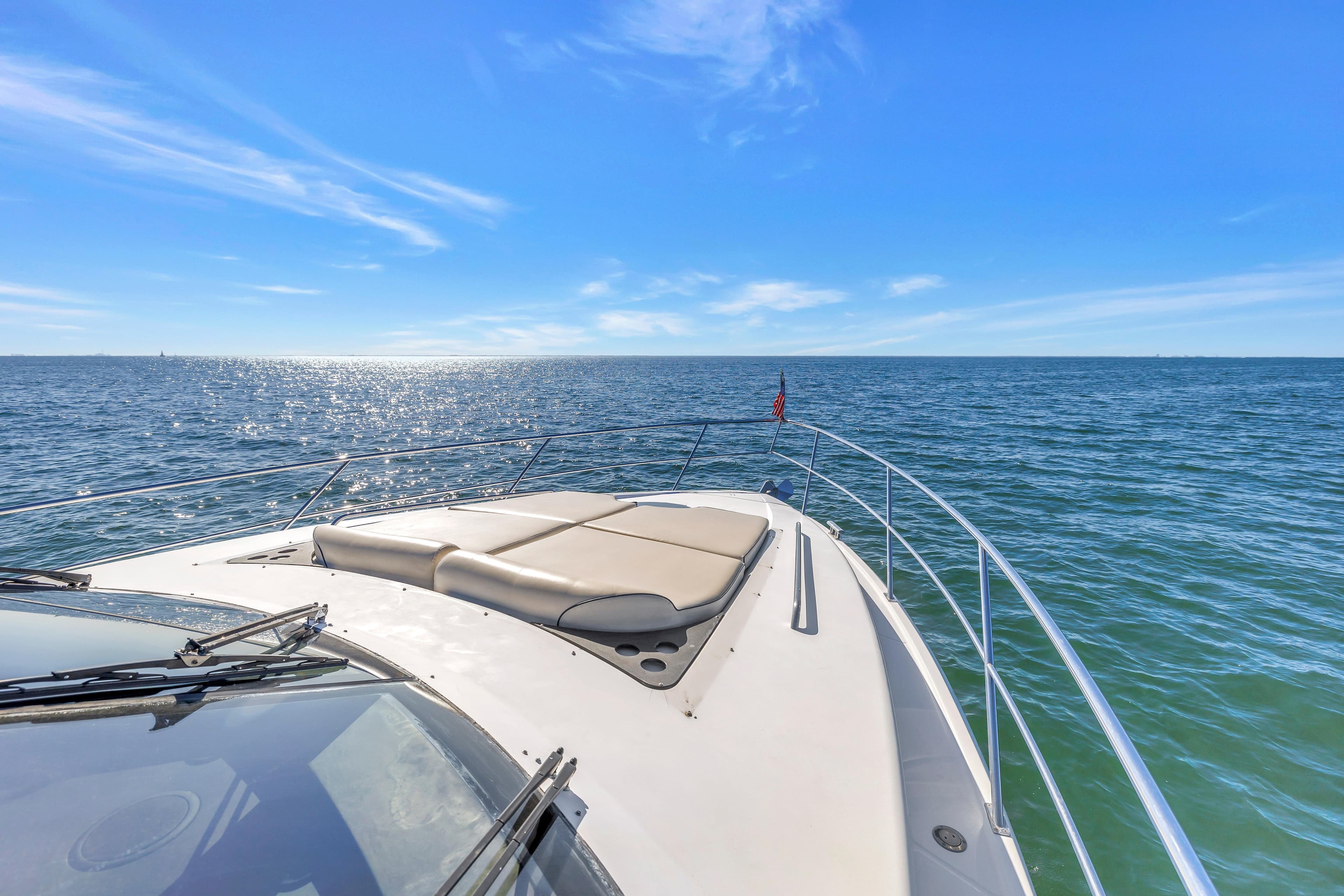 2001 Neptunus 56 Flybridge yacht cruising on open sea under clear blue sky.