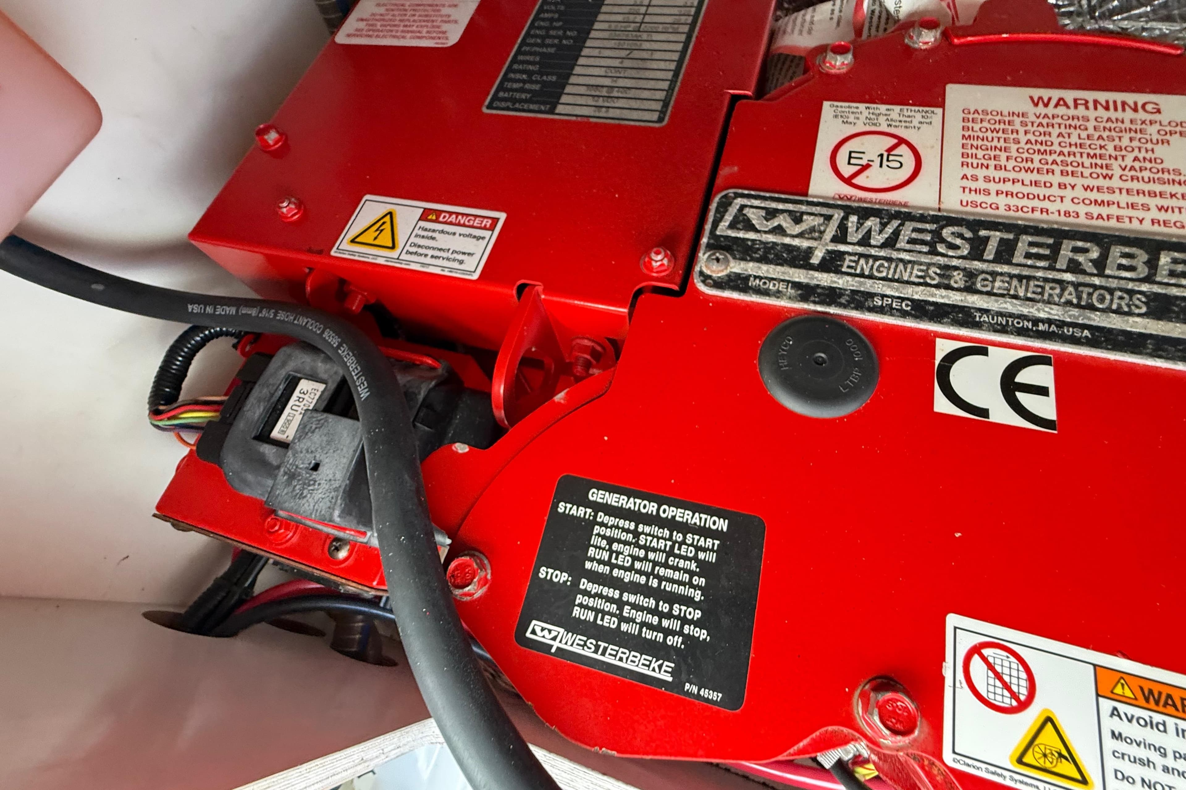 Red Westerbeke generator in a 2021 Jeanneau NC 895 boat, featuring safety labels and wiring.