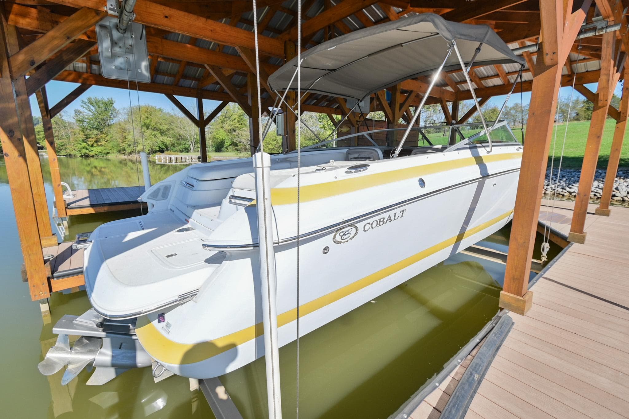 2002 Cobalt 262 boat docked under wooden shelter, side view.