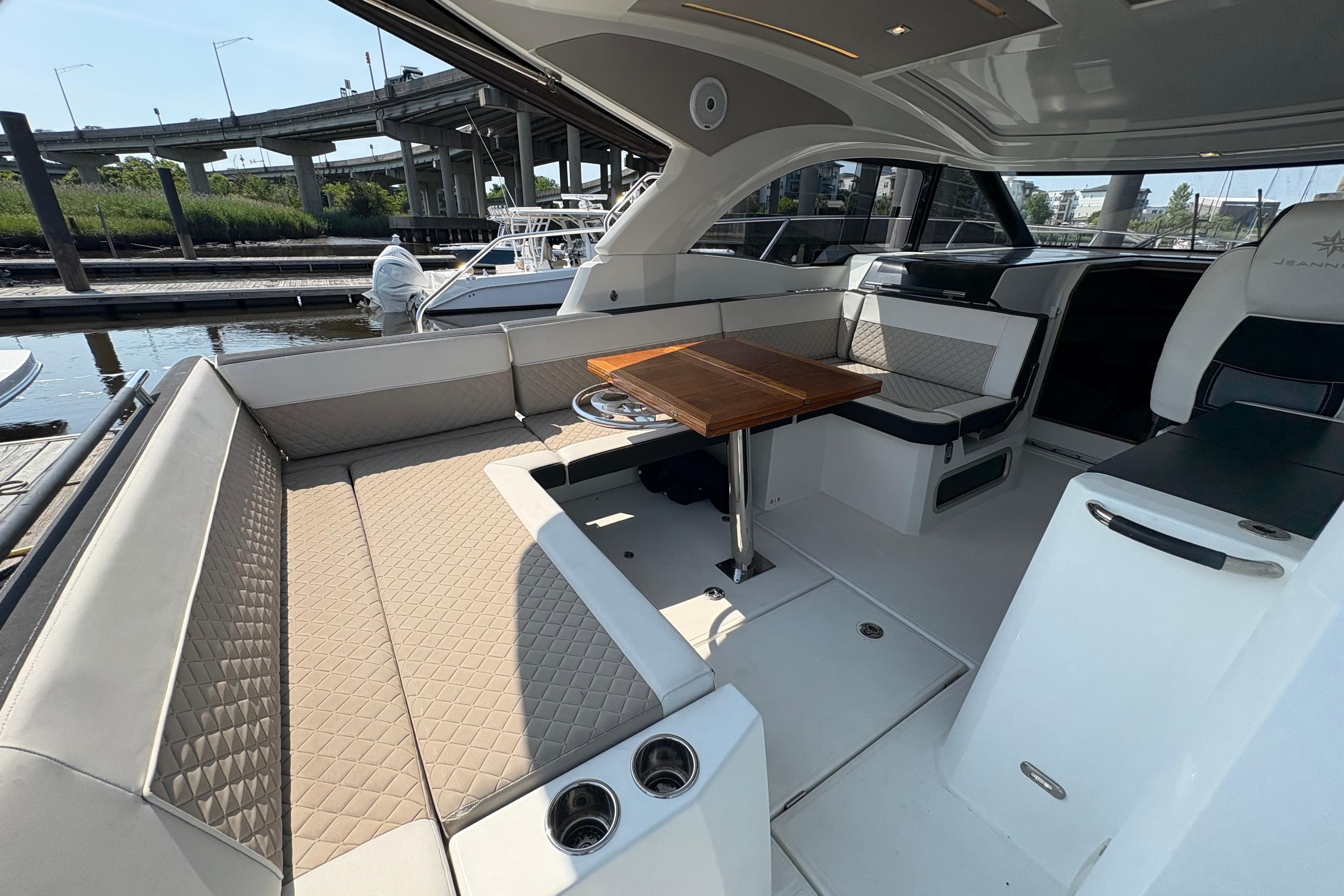 2018 Jeanneau Leader 33 yacht interior with elegant seating and wooden table in a marina setting.
