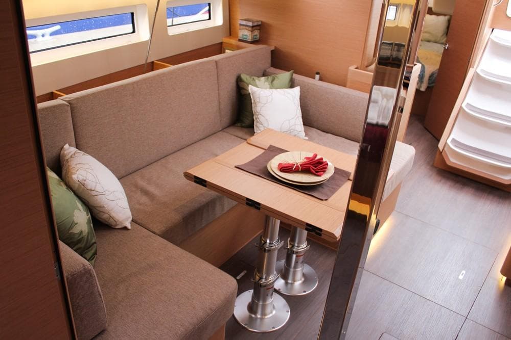 Interior of 2025 Jeanneau Sun Odyssey 440 yacht, featuring cozy seating and elegant dining area.