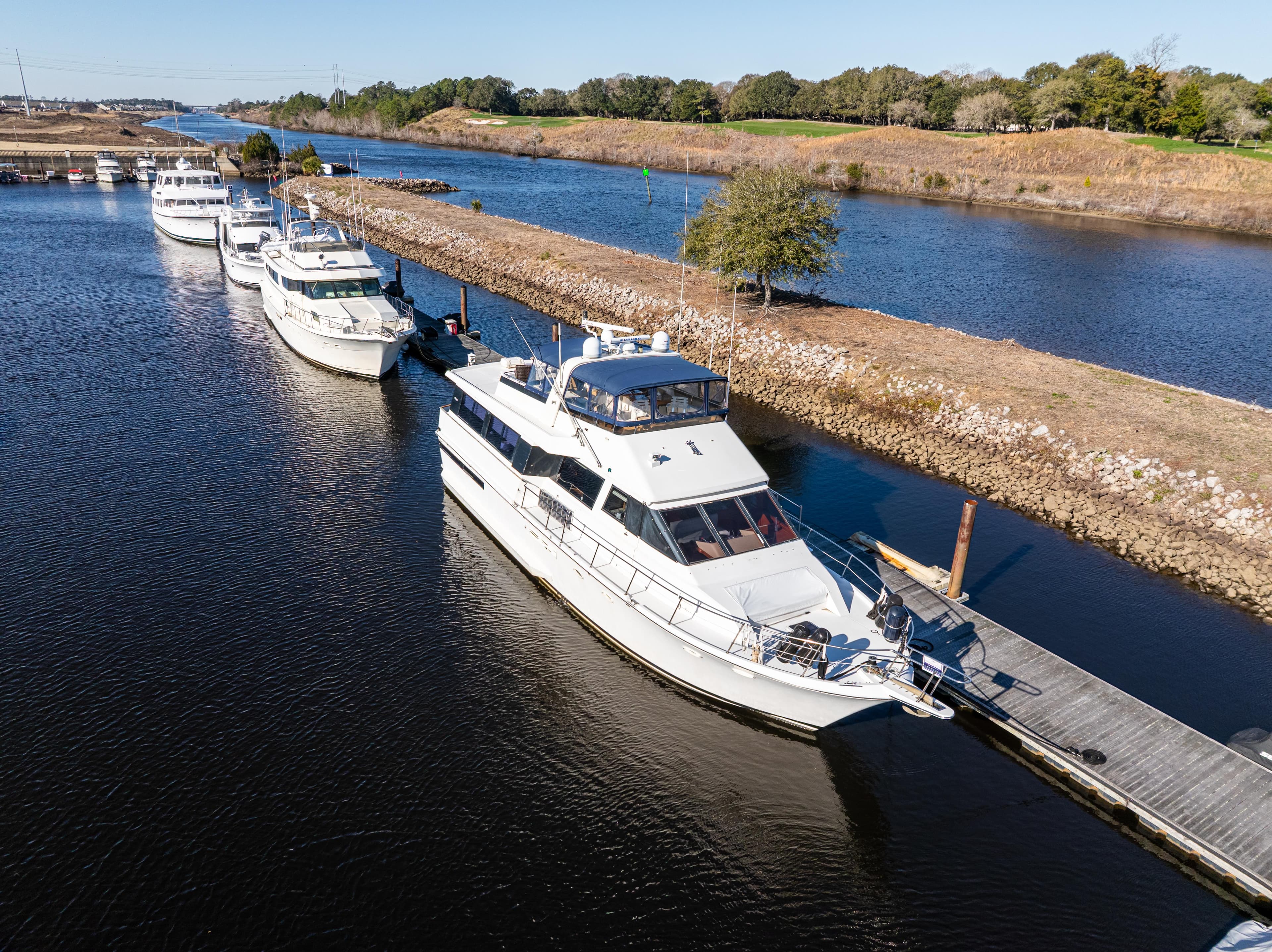 1989 Viking 63 Motor Yacht docked on a serene river with other boats.
