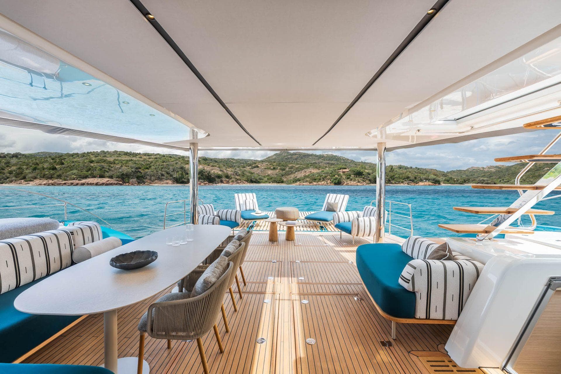 Manufacturer Provided Image: Luxurious Lagoon Eighty 2 yacht deck with elegant seating, overlooking serene blue waters and lush coastline.