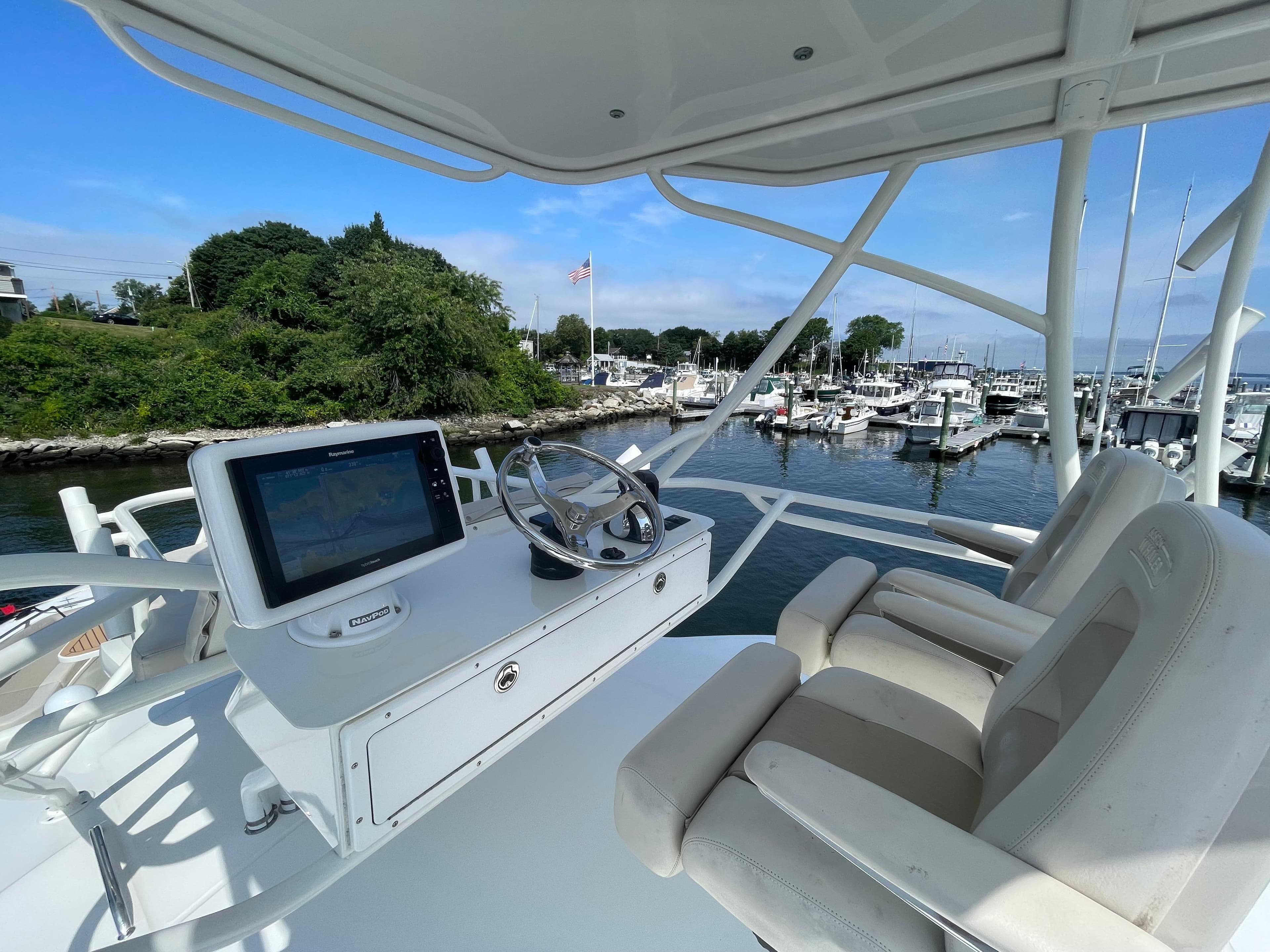 2017 Boston Whaler 420 Outrage helm with dual seats, overlooking marina and lush greenery.