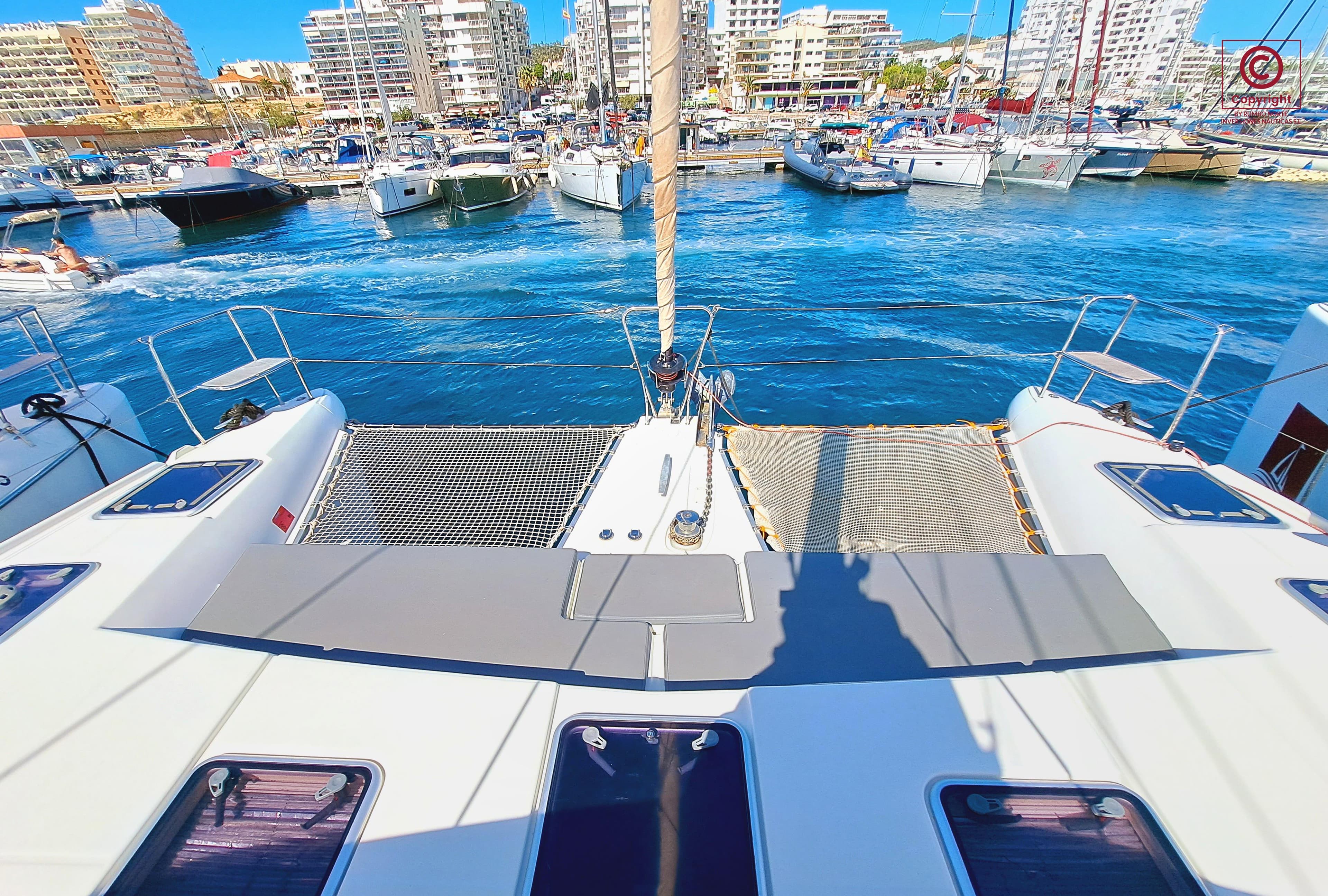 Lagoon 421 catamaran docked in a bustling marina, surrounded by boats and cityscape.