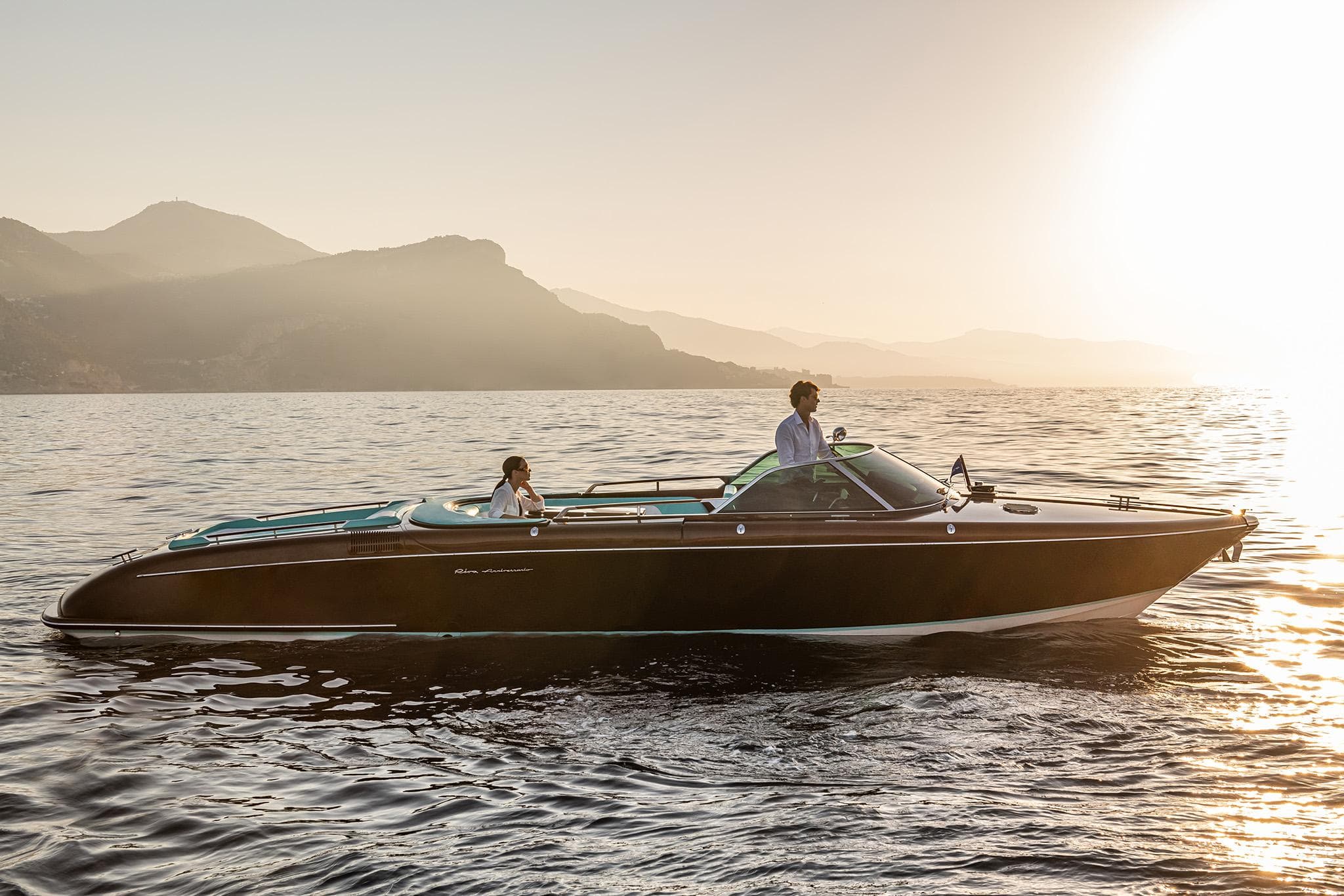 2023 Riva Anniversario boat cruising on serene waters at sunset.