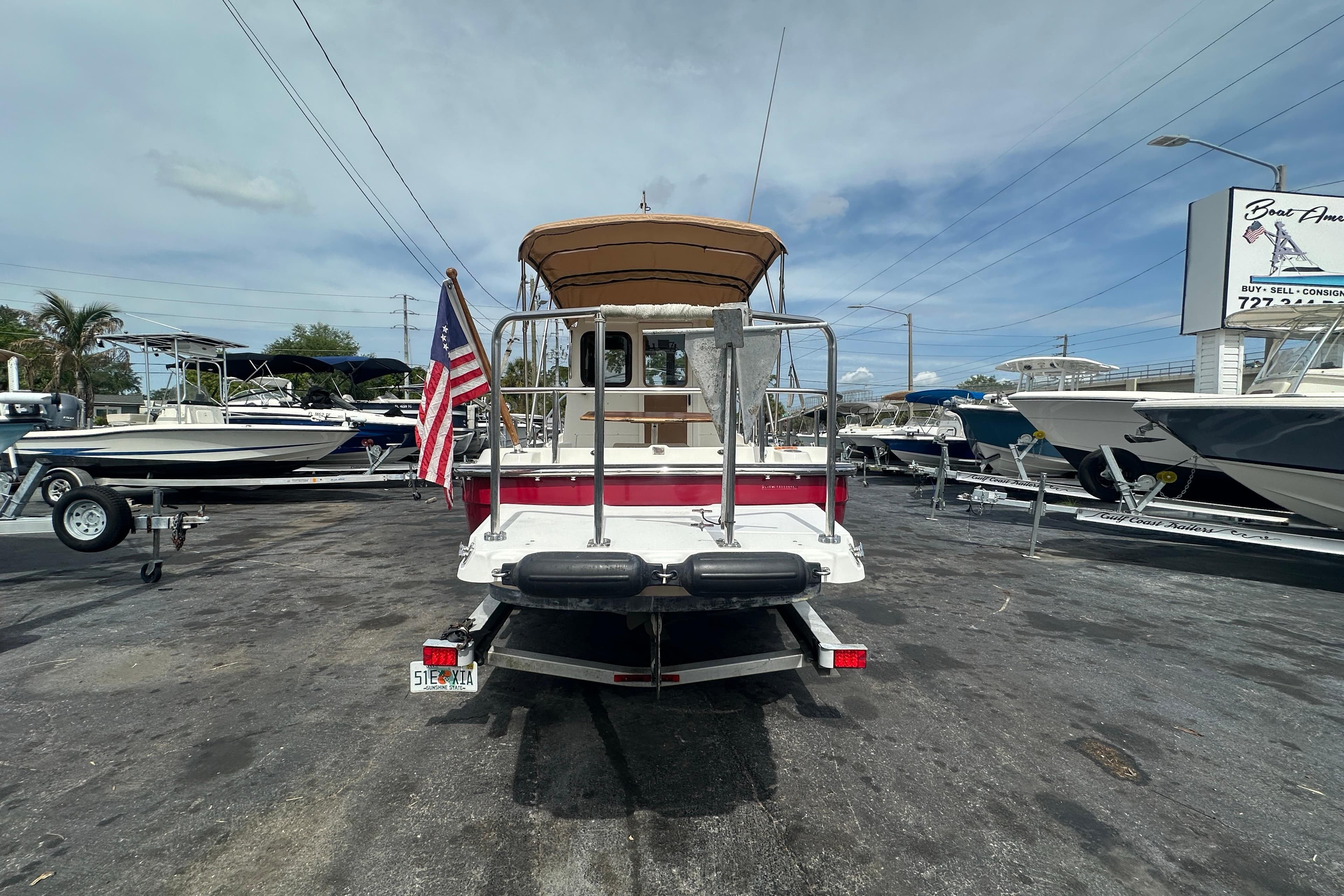 2015 Ranger Tugs R-21 EC boat displayed at a dealership with American flag.