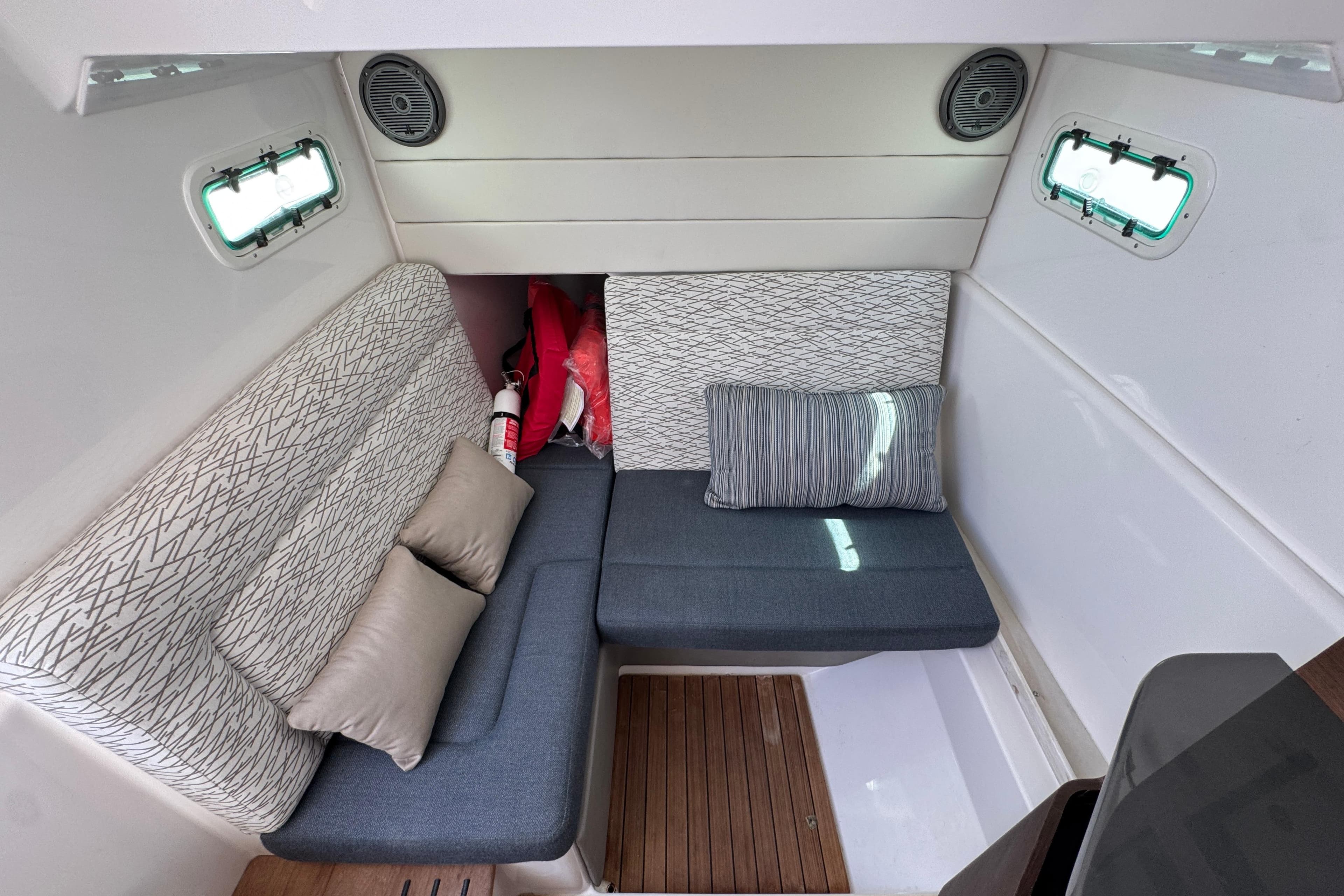 Interior cabin of 2019 Everglades 435 Center Console with cushioned seating and portholes.