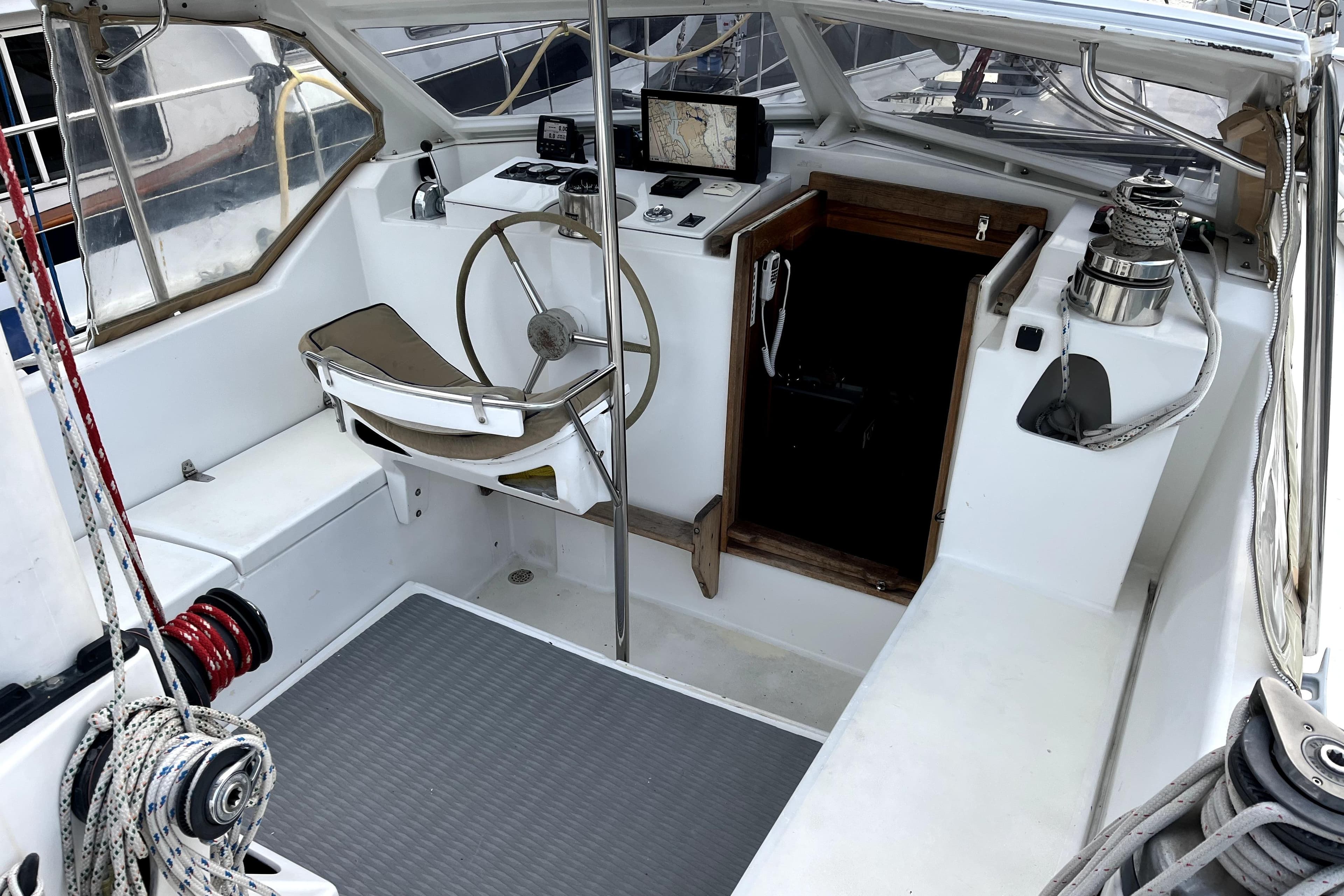 1979 Amel Mango sailboat cockpit with steering wheel, navigation equipment, and winches.