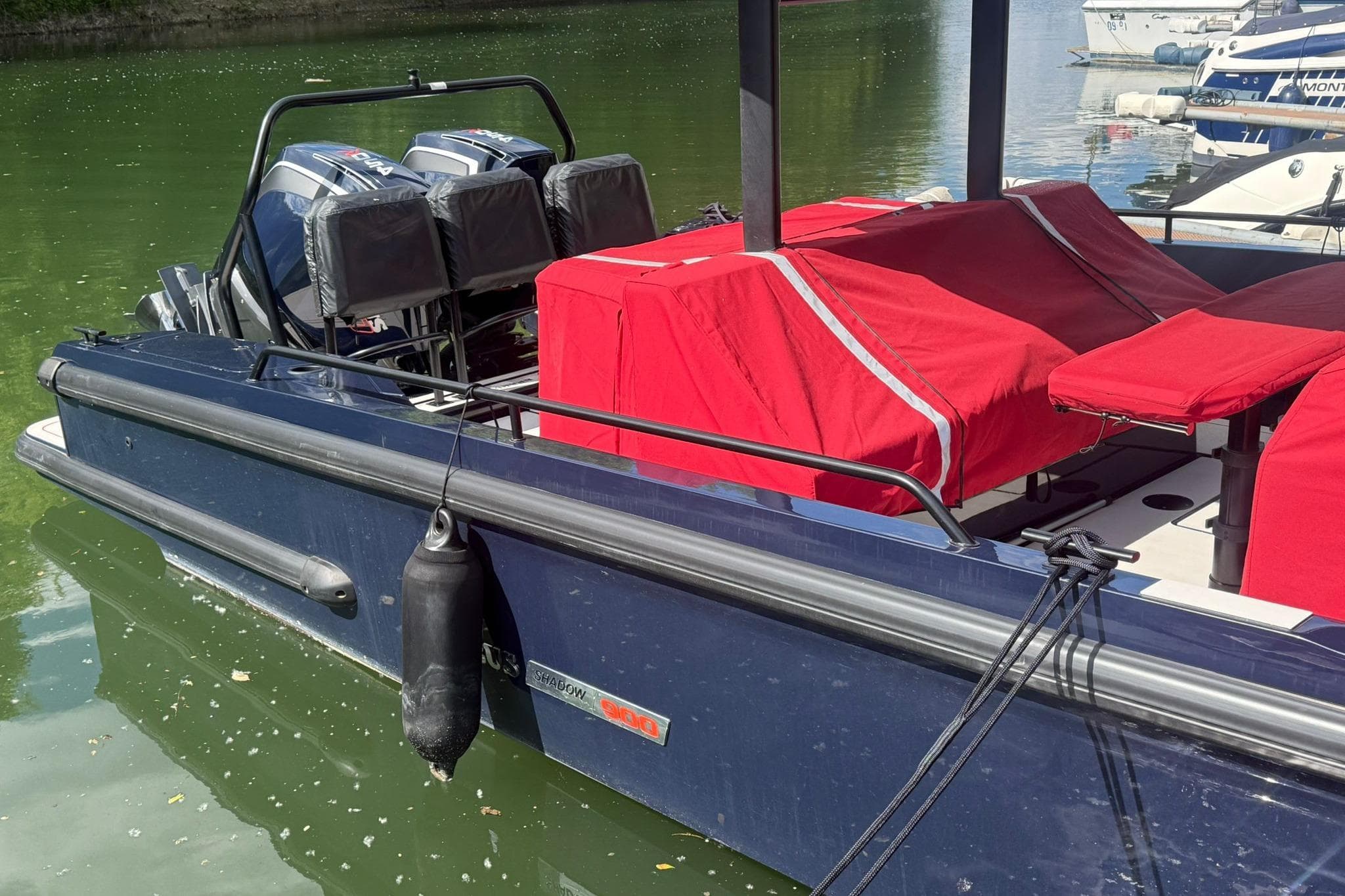 2022 Axopar Brabus Shadow 900 Sun-Top boat with red covers docked on calm water.