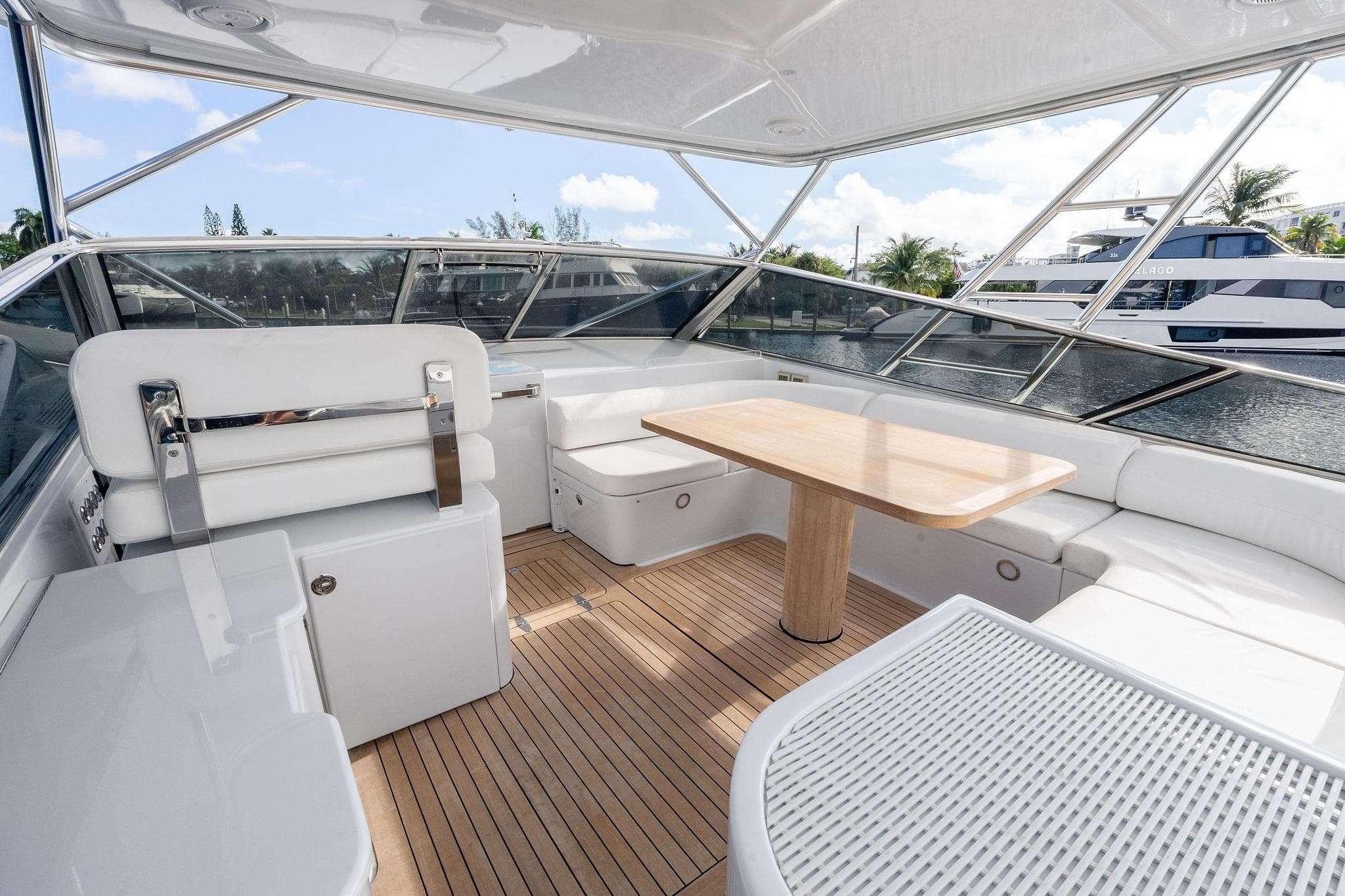 Luxurious interior of a 1995 Itama 46 yacht with white seating and wooden table.