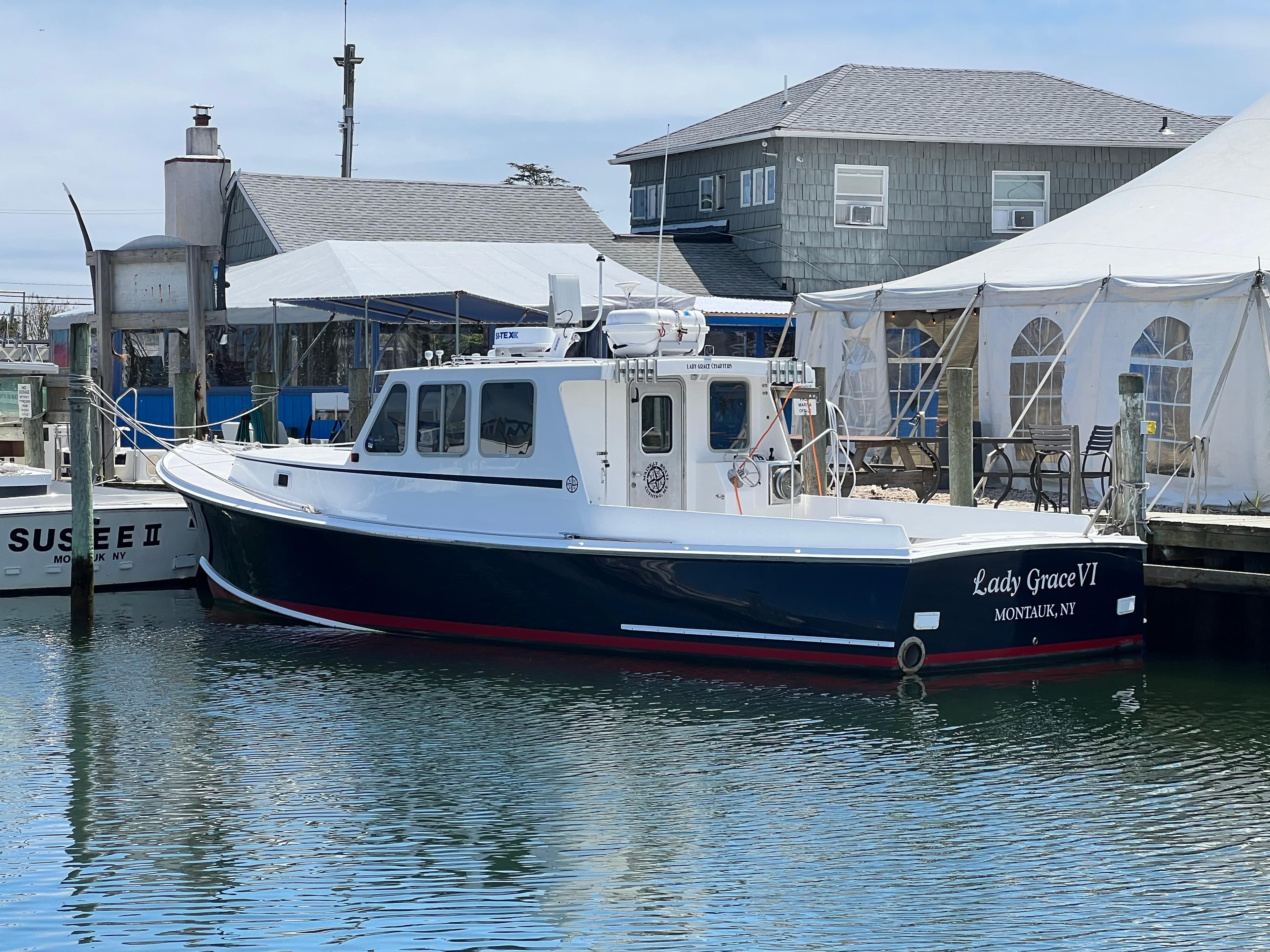 Wesmac 38 boat, 2022 model, docked near waterfront buildings and tents.