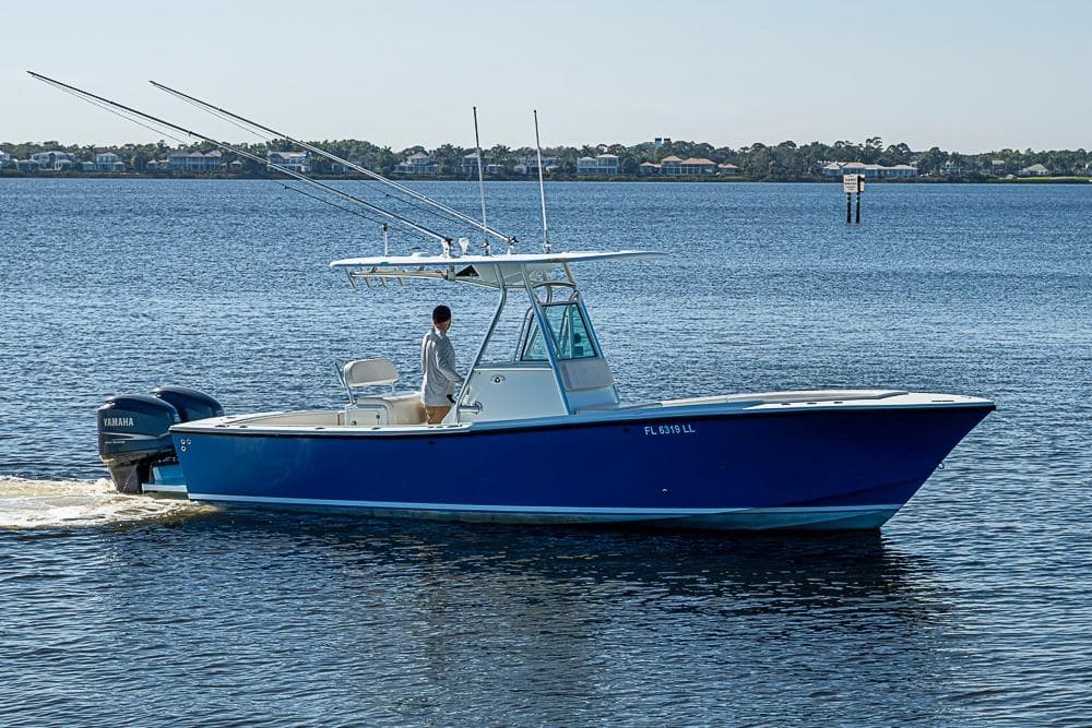 2000 Regulator 26 Forward Seating boat cruising on calm water with fishing rods.
