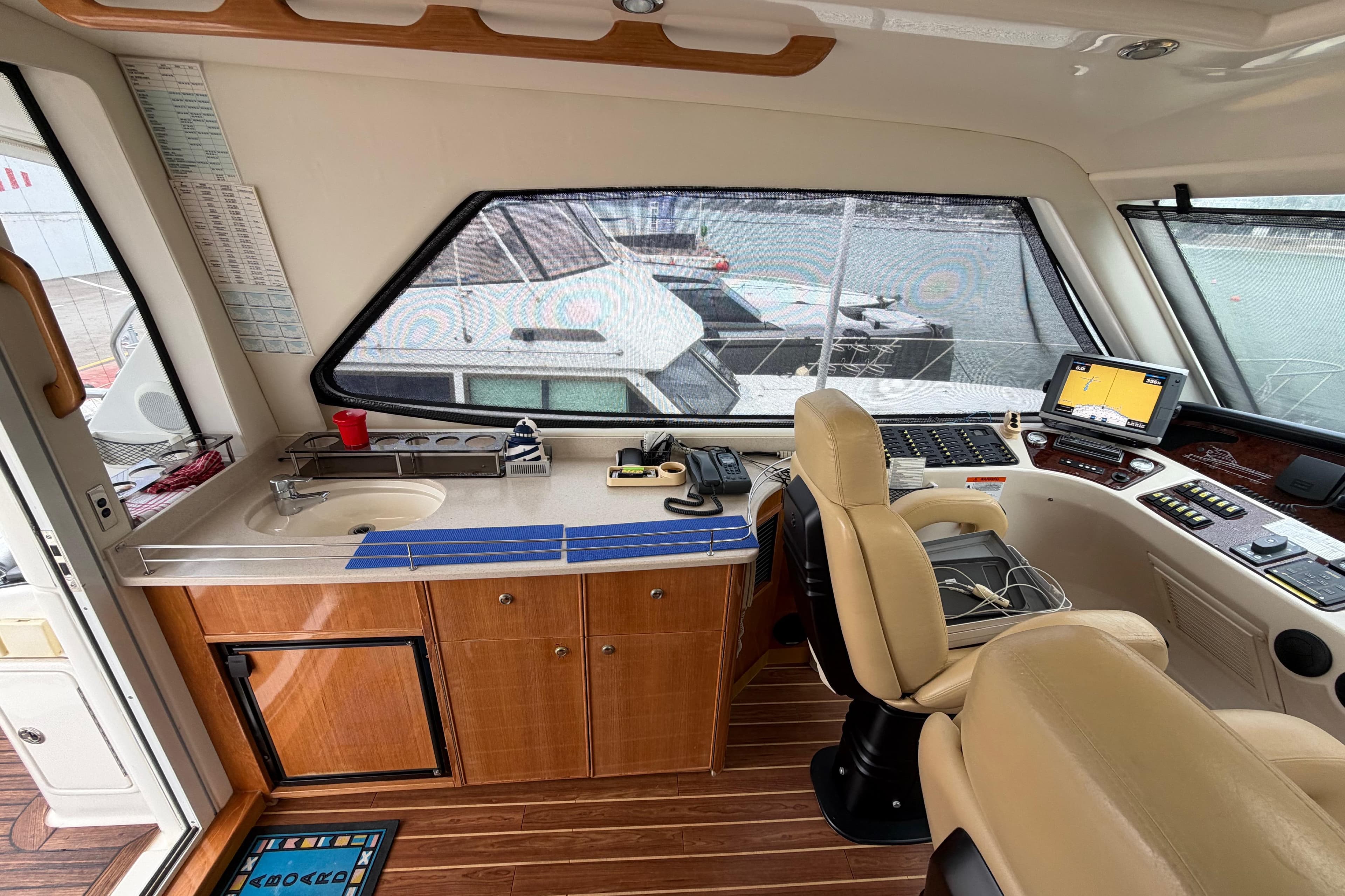 Interior of 2004 Riviera 60 Flybridge yacht with helm, navigation equipment, and kitchenette.