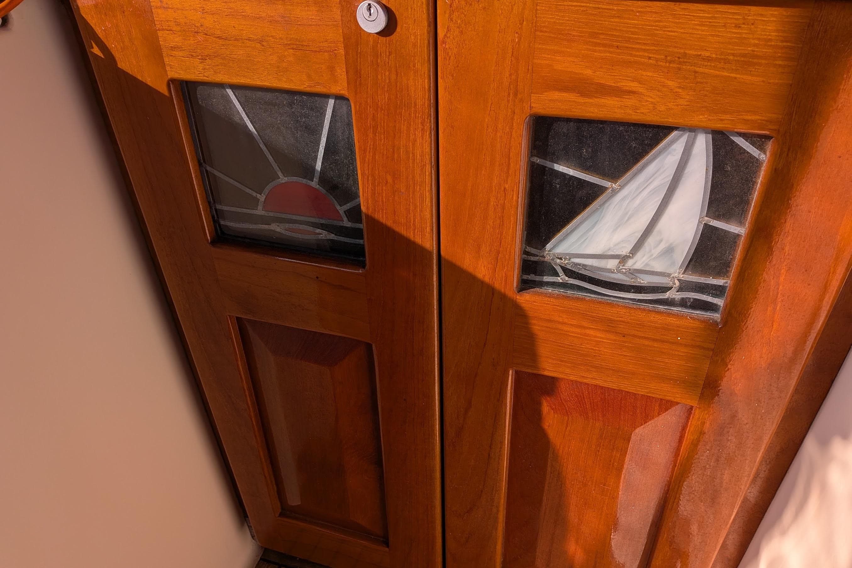 Wooden door with stained glass panels featuring a sailboat and sunset, Gozzard 37, 2003.