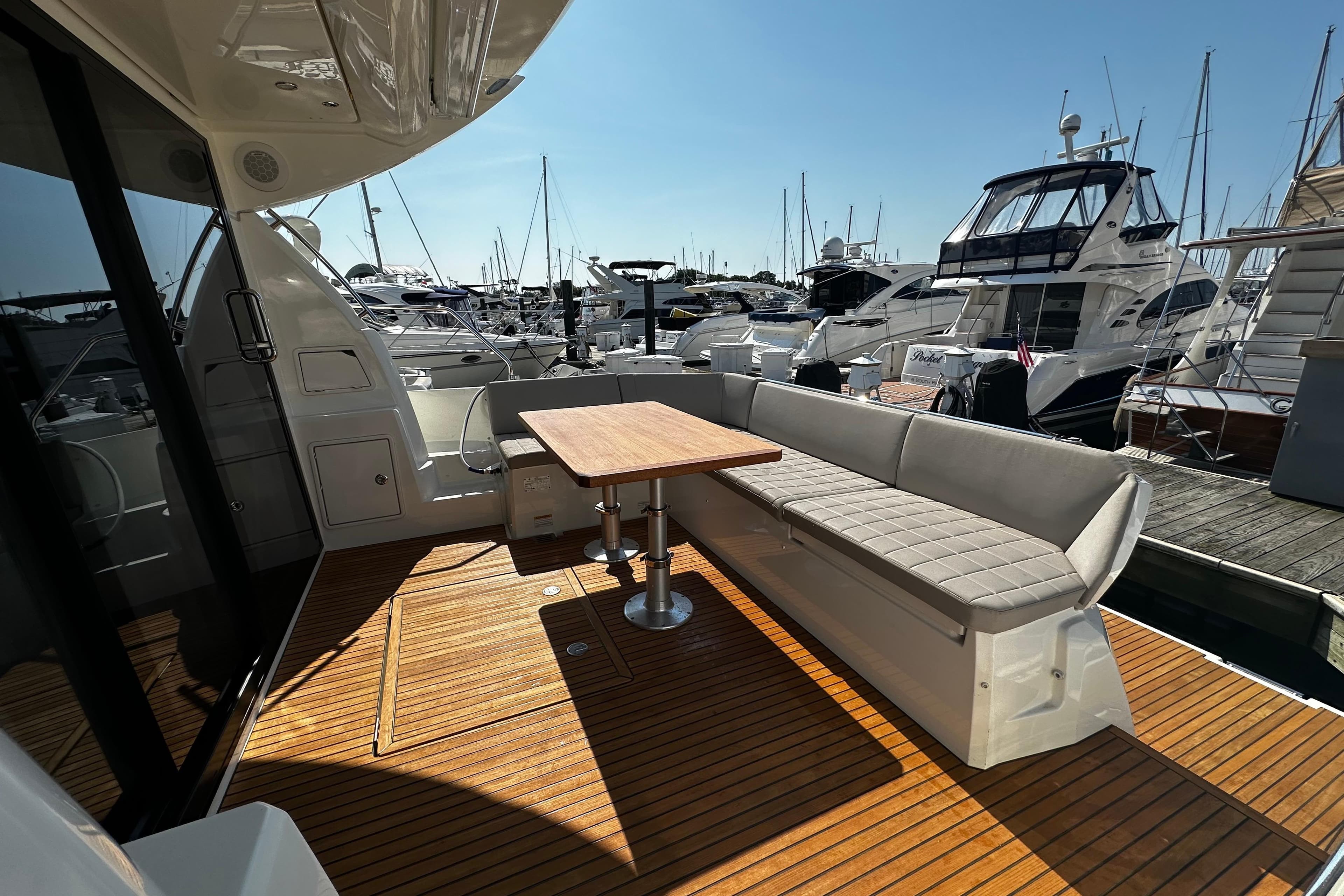 Luxurious 2018 Prestige 460 yacht deck with seating and table, docked at marina.